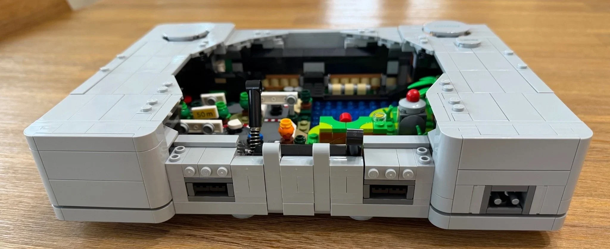 Rear casing and connection details on the partly built LEGO PlayStation, with the game scenes visible inside.
