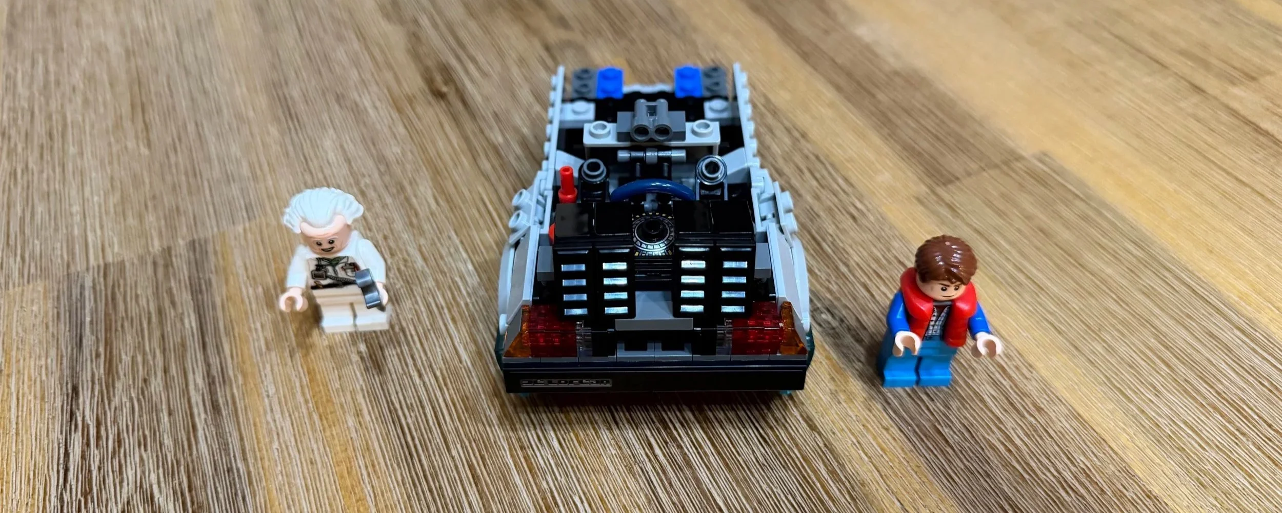 Rear view of the LEGO DeLorean during assembly, showing black vents, red taillights, and an unfinished cabin.