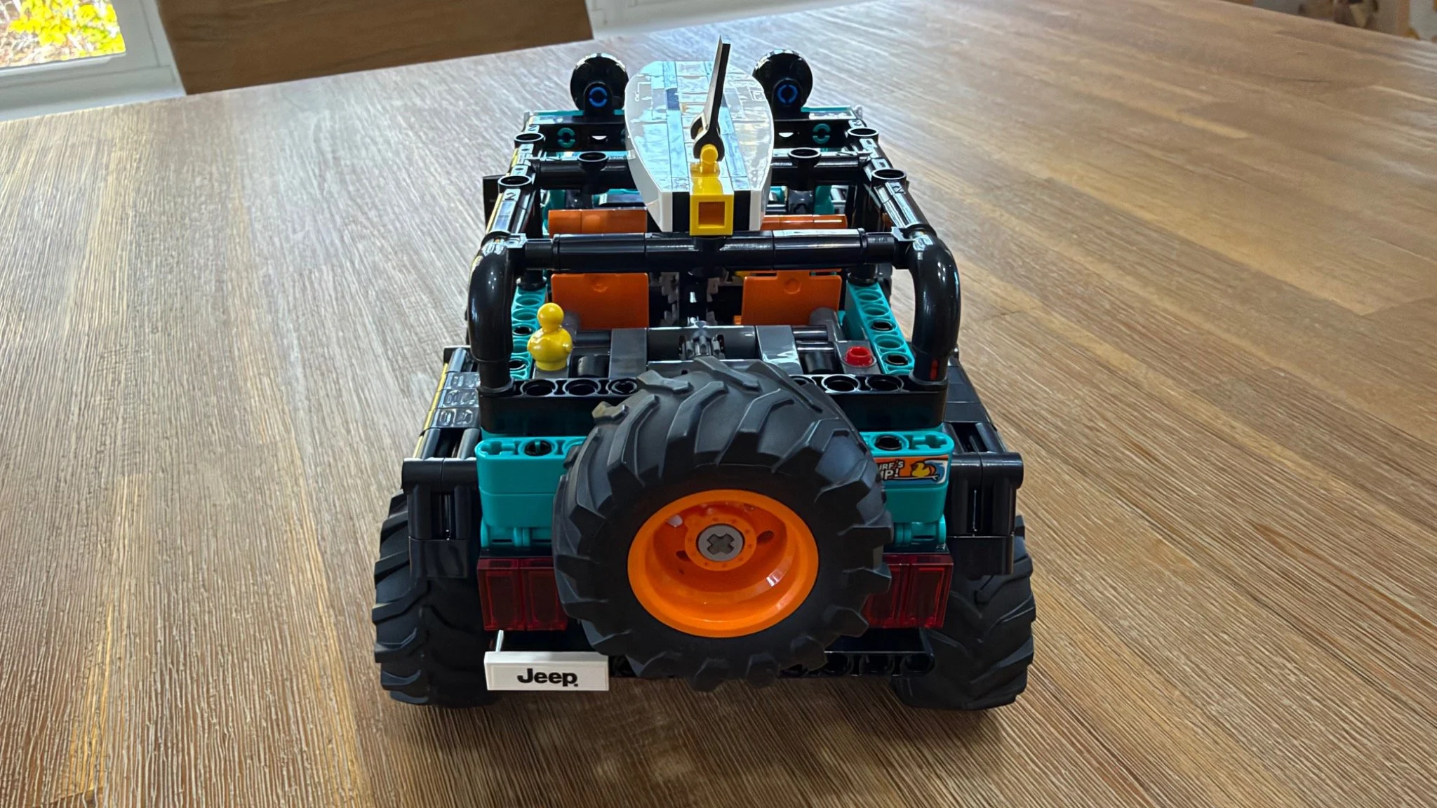 Rear of completed LEGO Jeep Wrangler Rubicon 42227 with orange-centered spare tire, yellow duck behind the seats and surfboard above the roll cage.