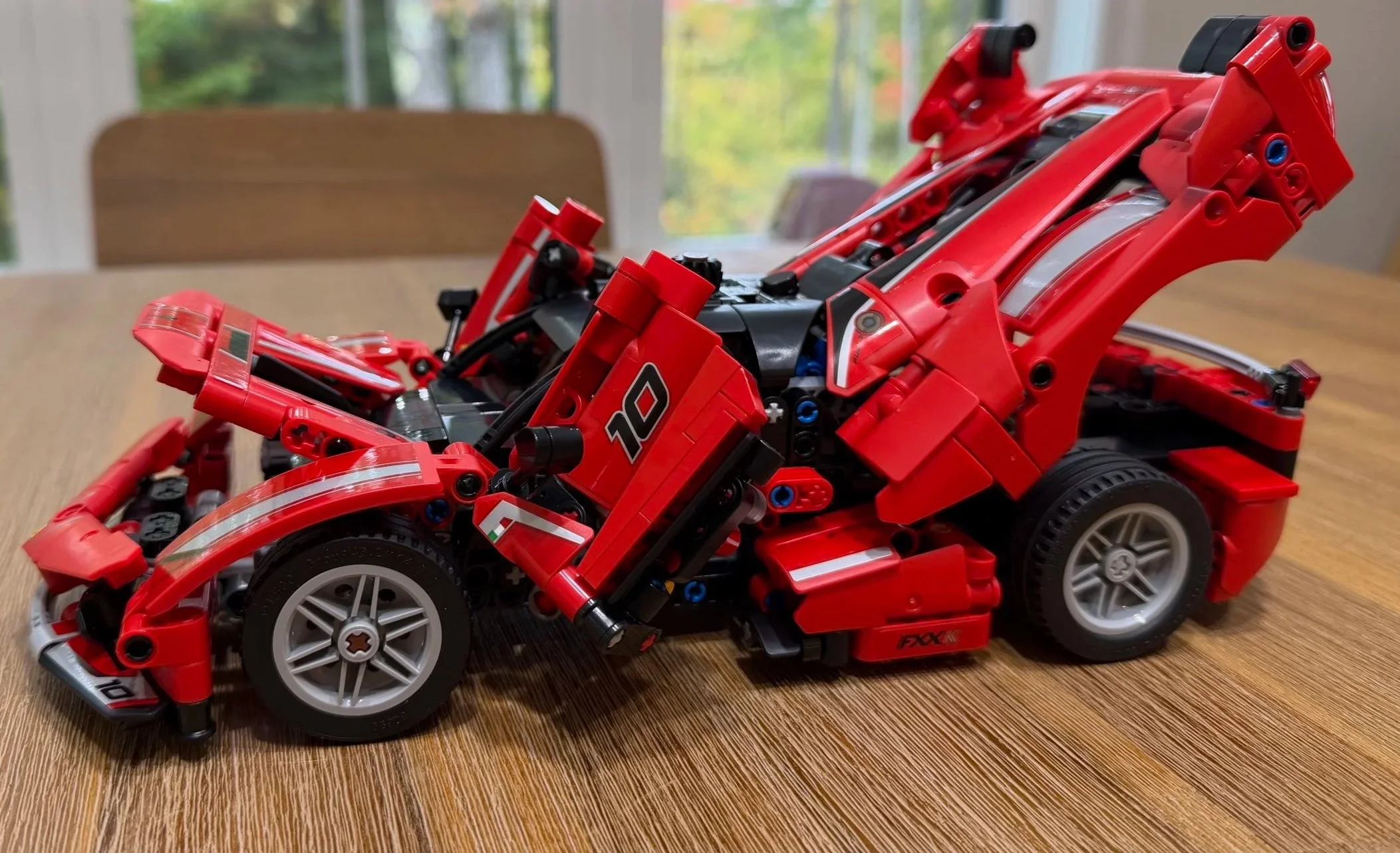 Completed red LEGO Ferrari FXX K with both butterfly doors, the front hood, and rear engine cover open, showing the number 10 door graphic.