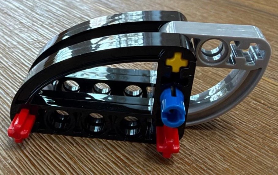 Black and gray curved Technic guide for LEGO Donkey Kong Arcade 72051 joined by red and yellow axles.