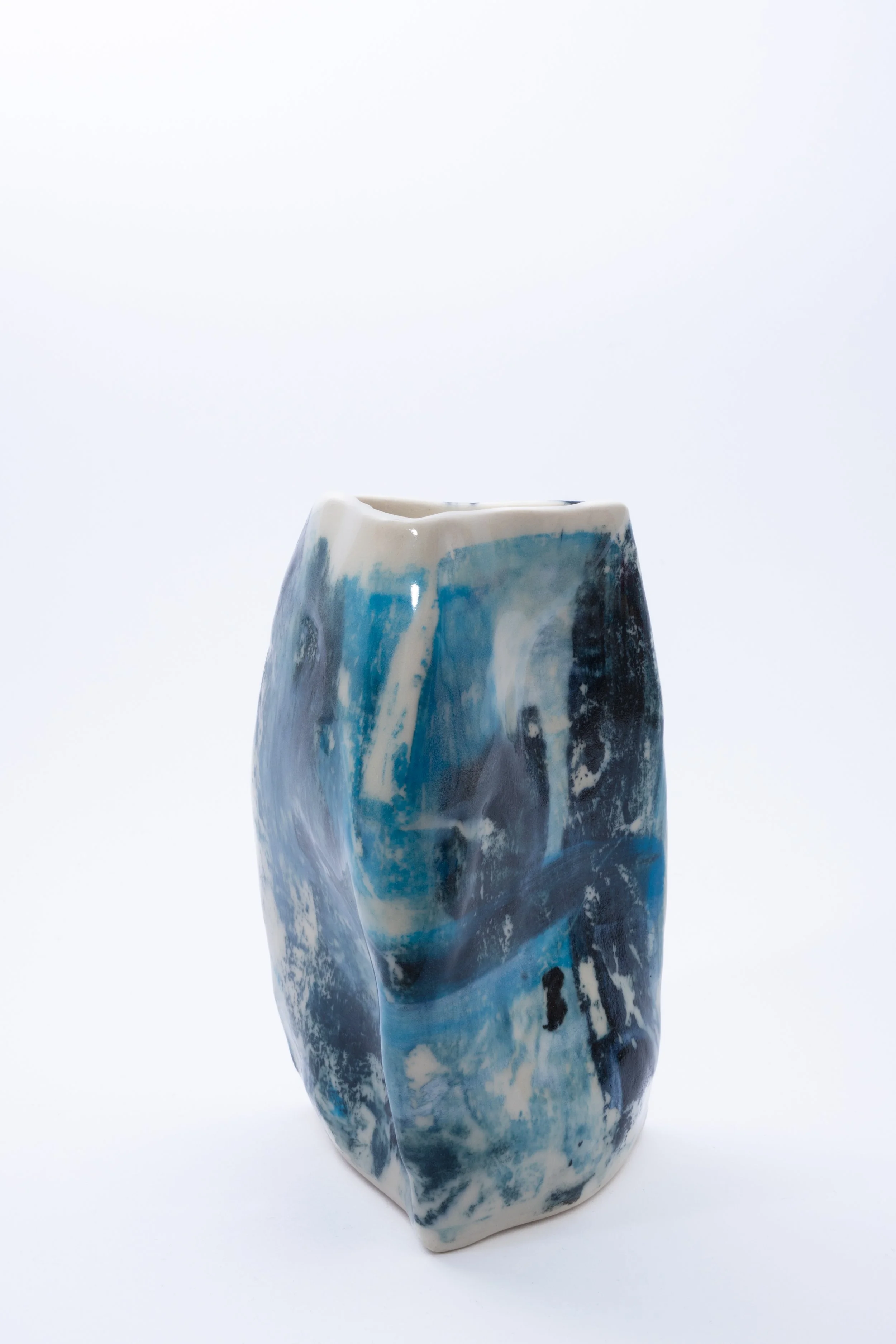 Ceramic vase with abstract blue, black, and white glaze on a white background