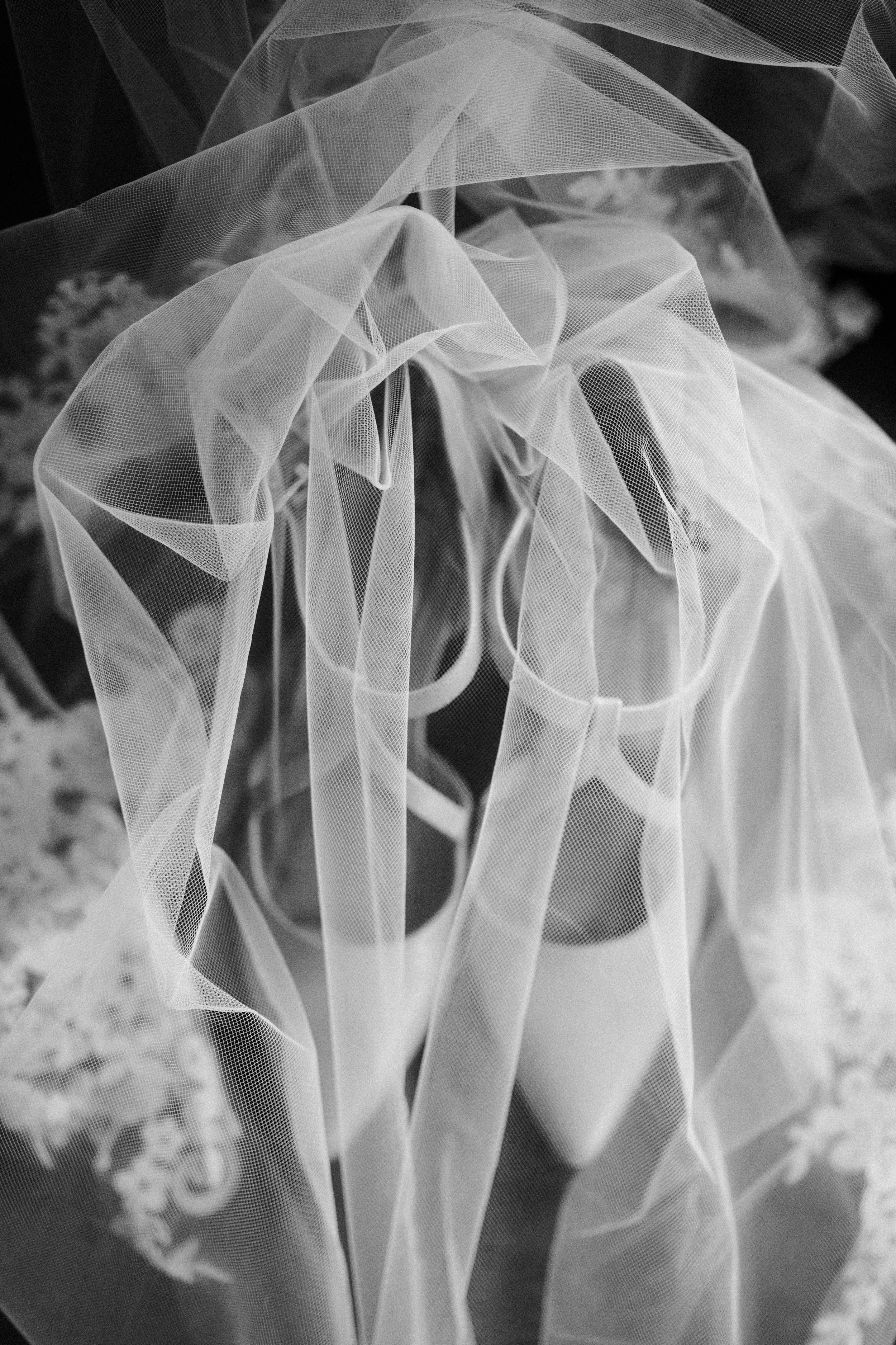 A pair of white high-heeled shoes under a sheer, flowing wedding veil. Edmonton Wedding and Event Planner.