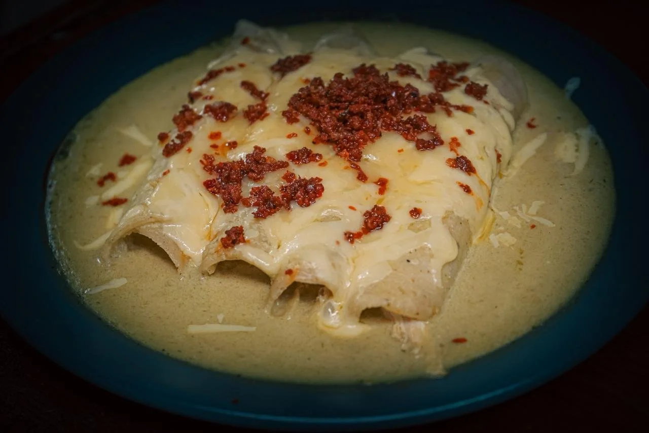 Ensalada de enchiladas cubiertas con queso y tocino en un plato azul.