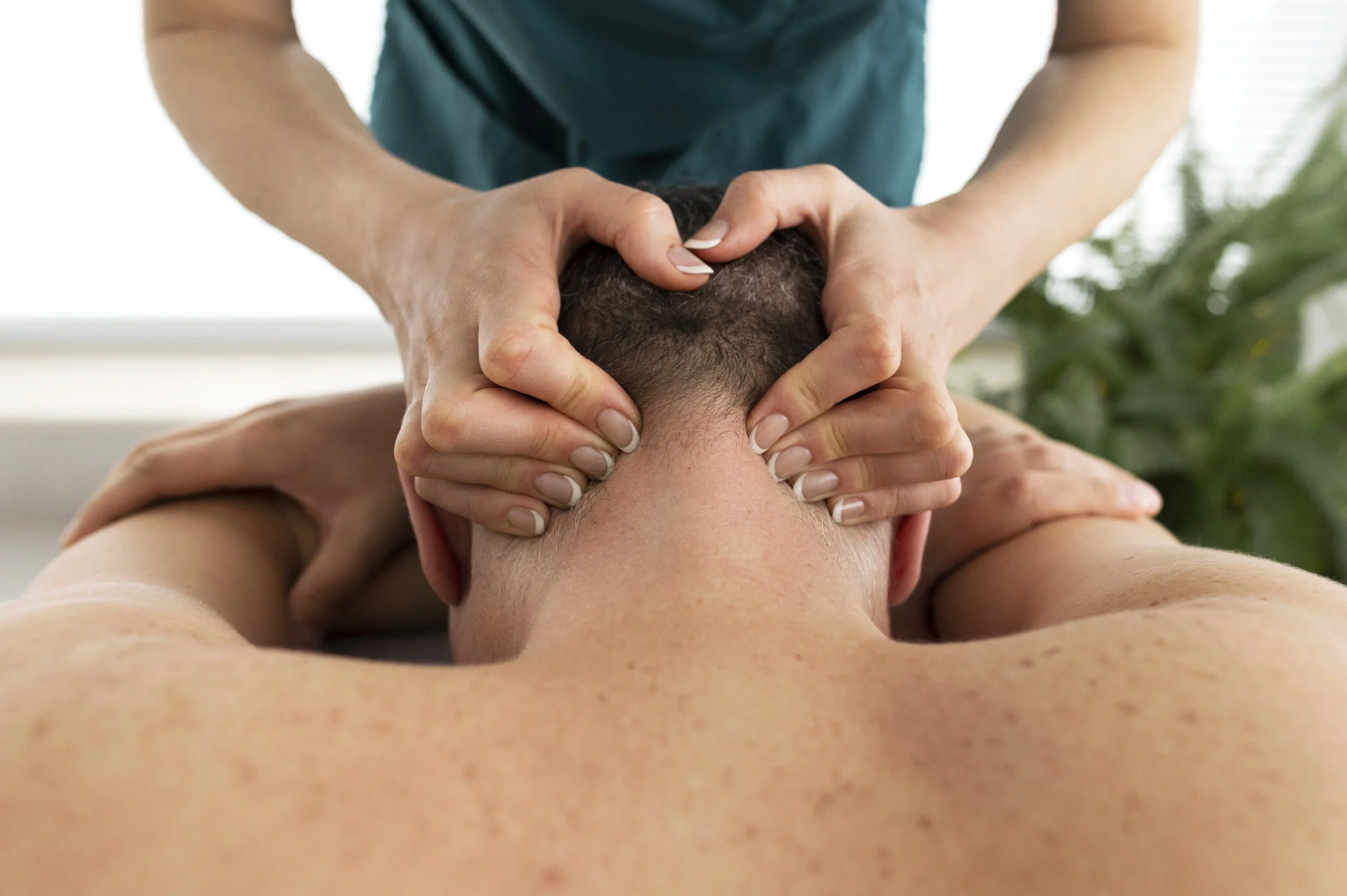 Persona recibiendo un masaje en la zona del cuello durante una terapia de masajes.