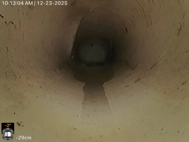 The image shows the inside of a pipe or a cylindrical tunnel with a small pool of water at the bottom.