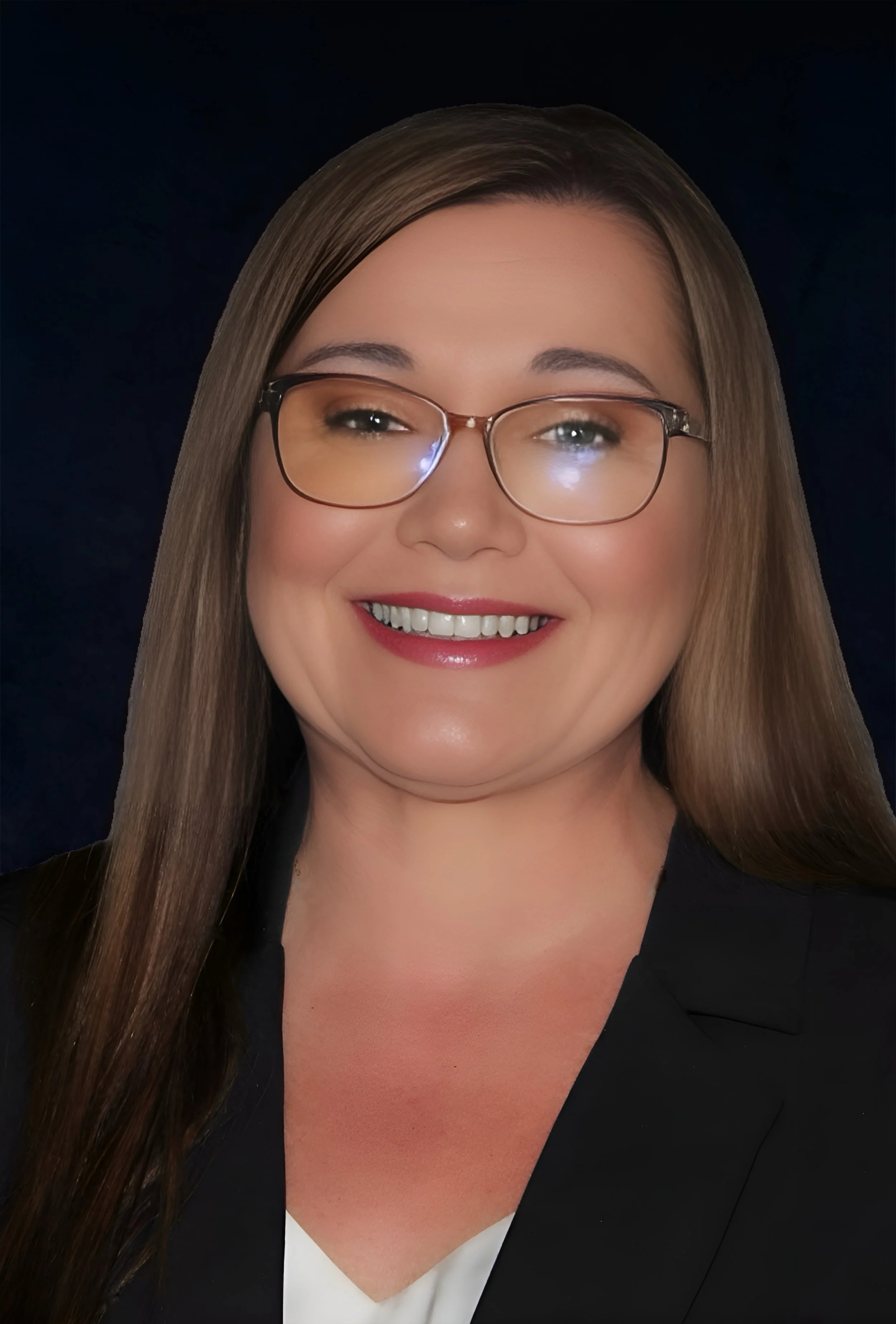 A woman with long brown hair, wearing glasses, a black blazer, and a white top, smiling against a dark background.