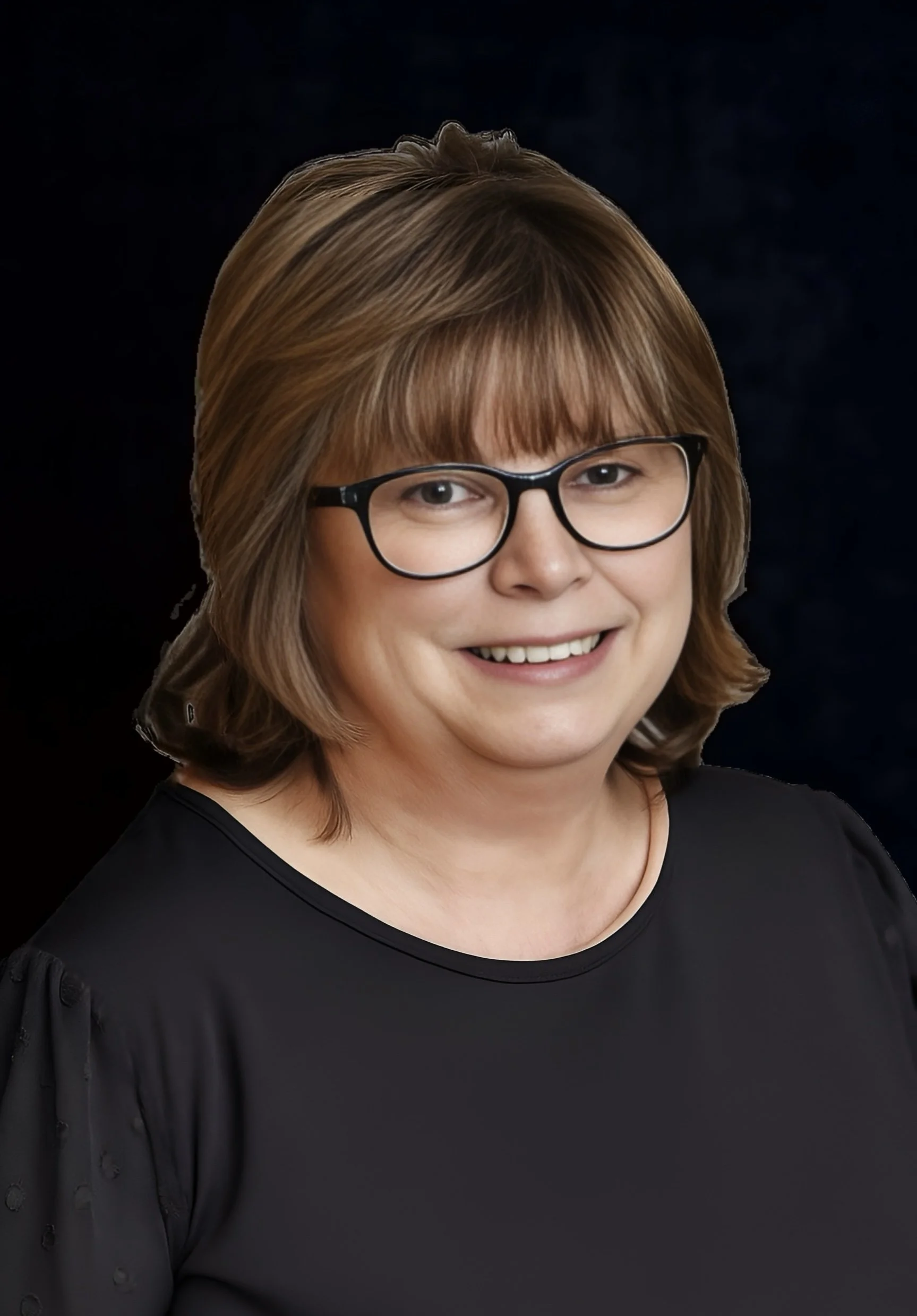 A woman with shoulder-length light brown hair, glasses, and a black blouse, smiling against a dark background.