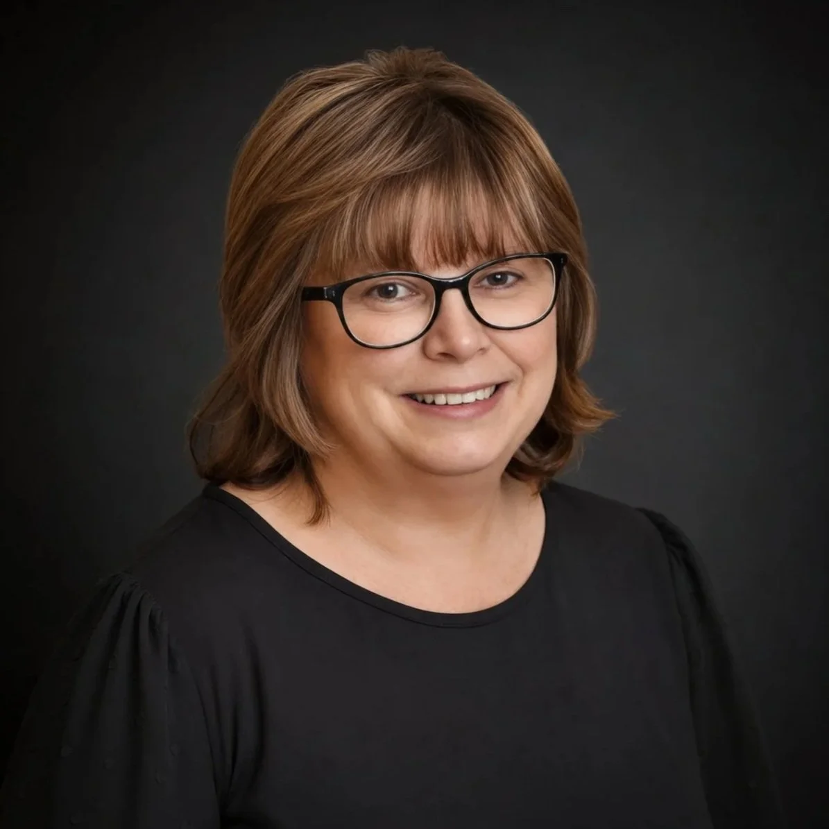 Headshot a smiling woman with short brown hair, black glasses, wearing a black top.
