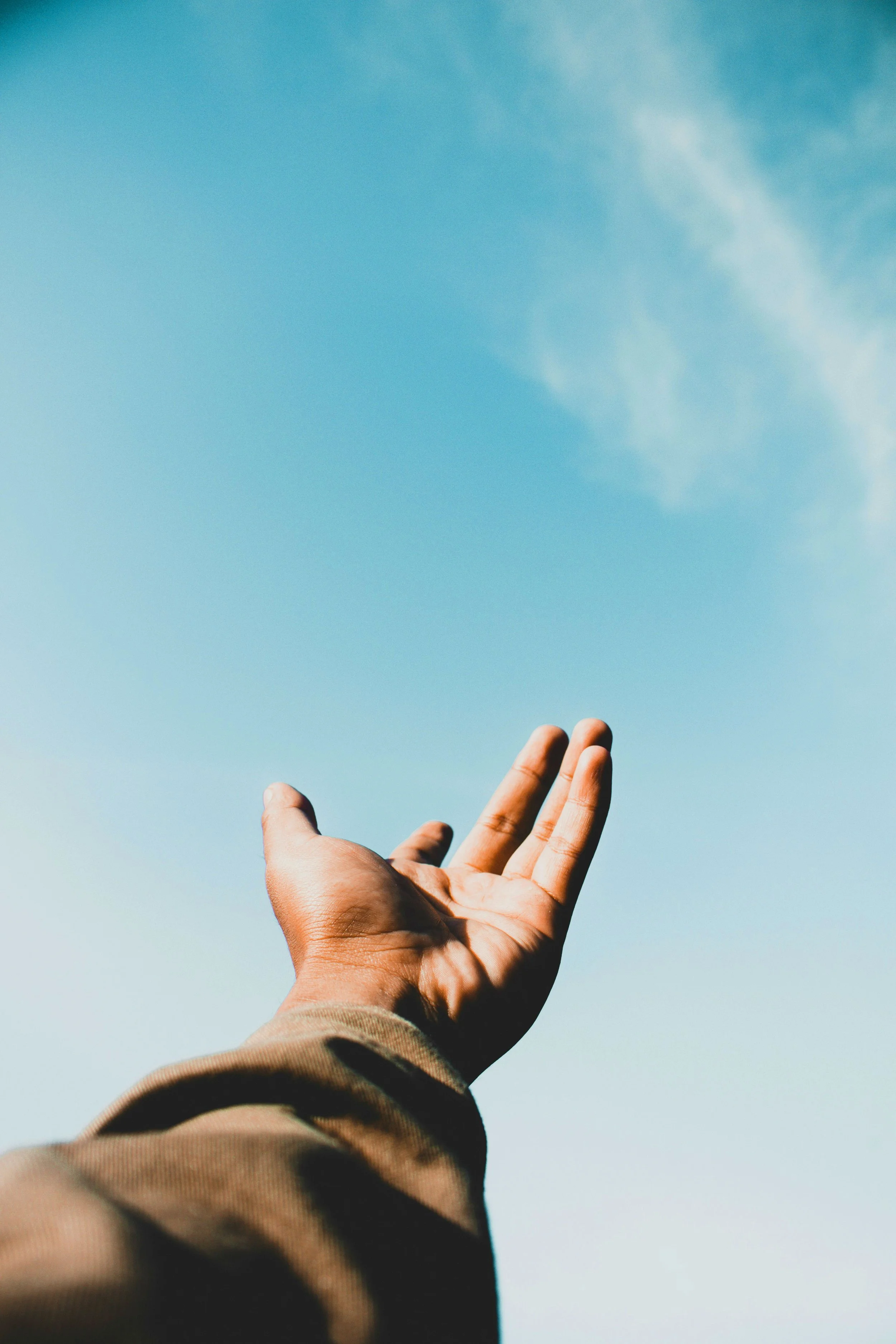 Woman reaching hand out to the blue sky