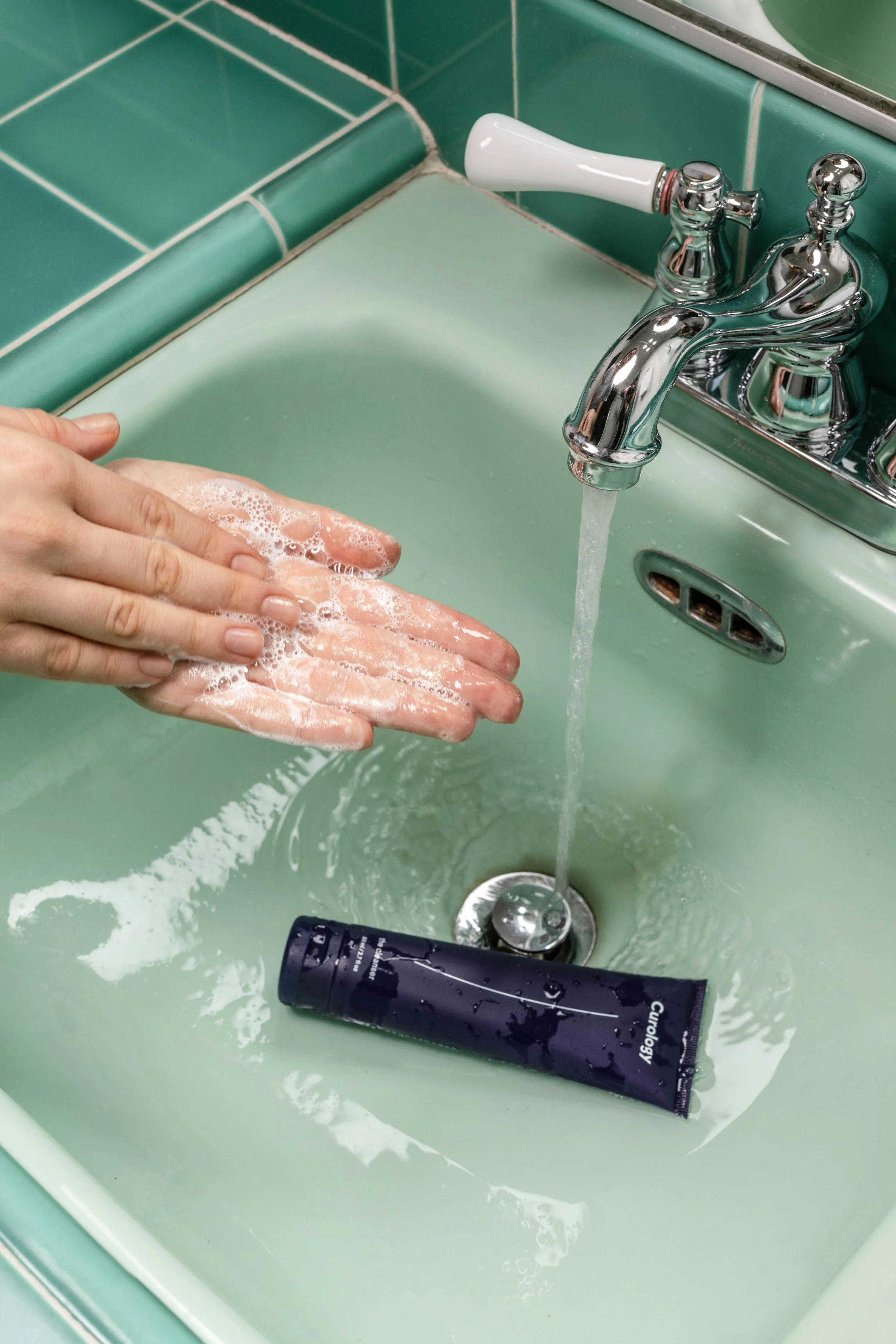 Woman washing hands in green sink