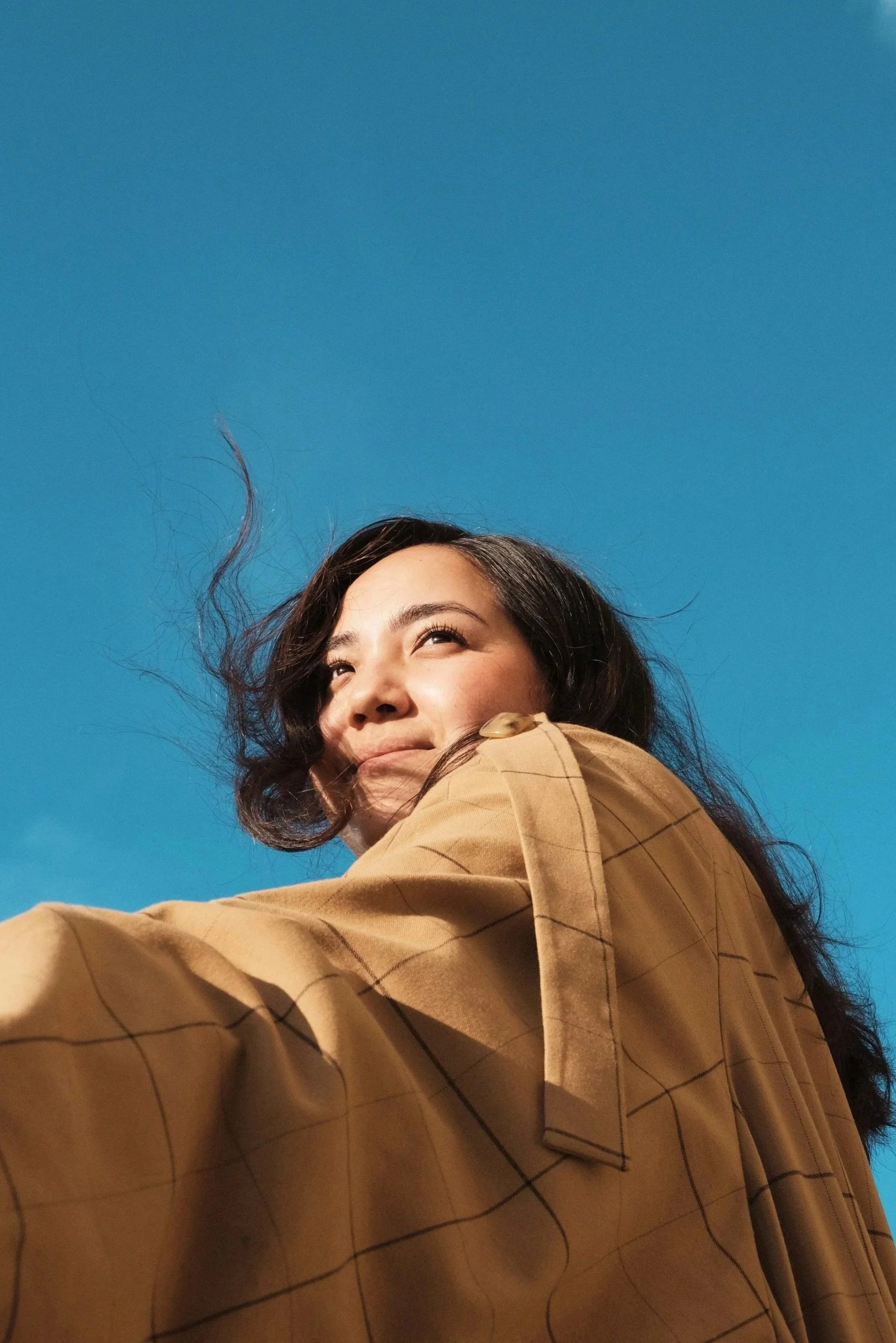 Woman smiling into the sunshine against blue sky