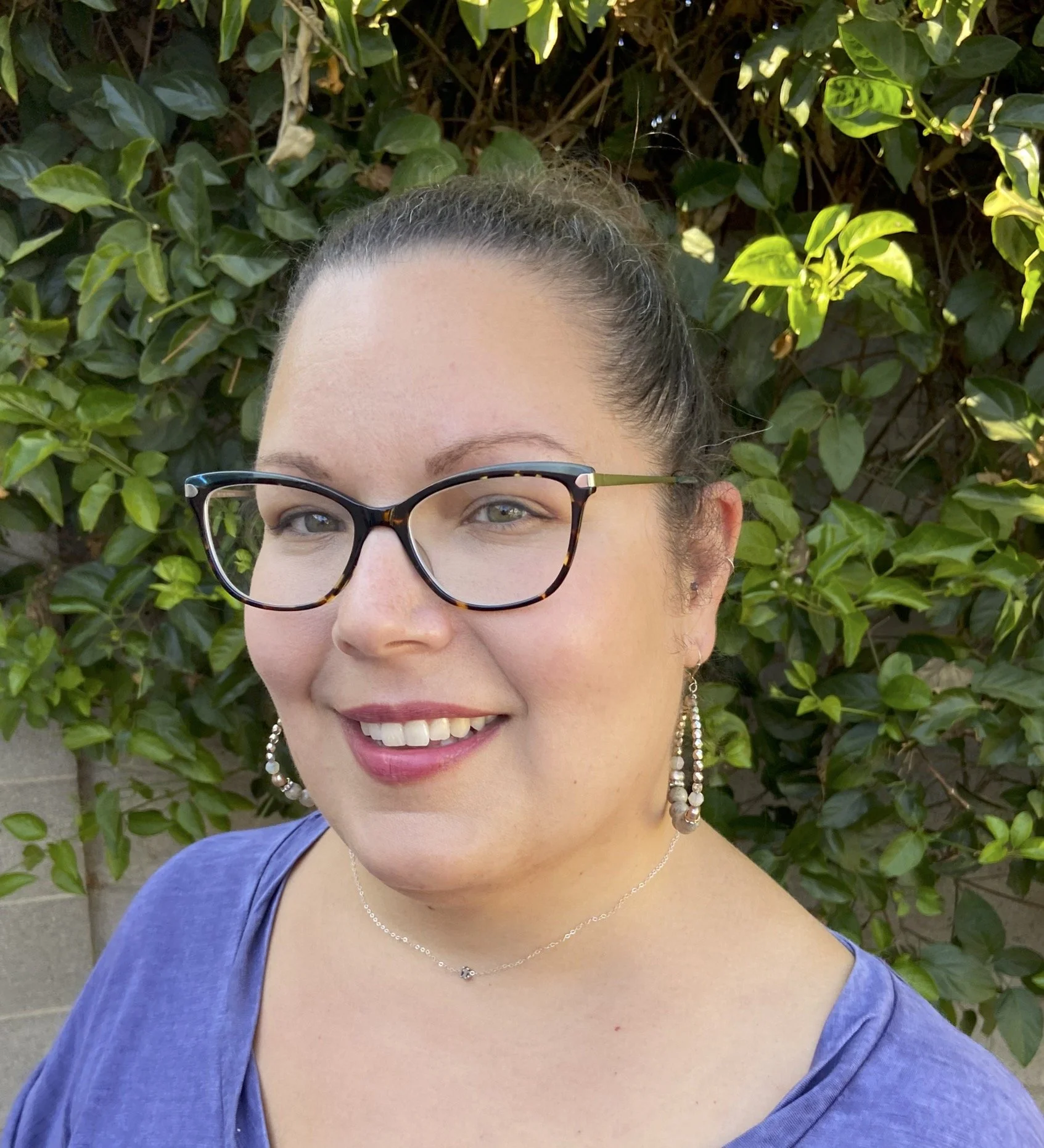 Photo of Ursula Hoefer, Acupuncturist, outdoors with green leaves in the background.