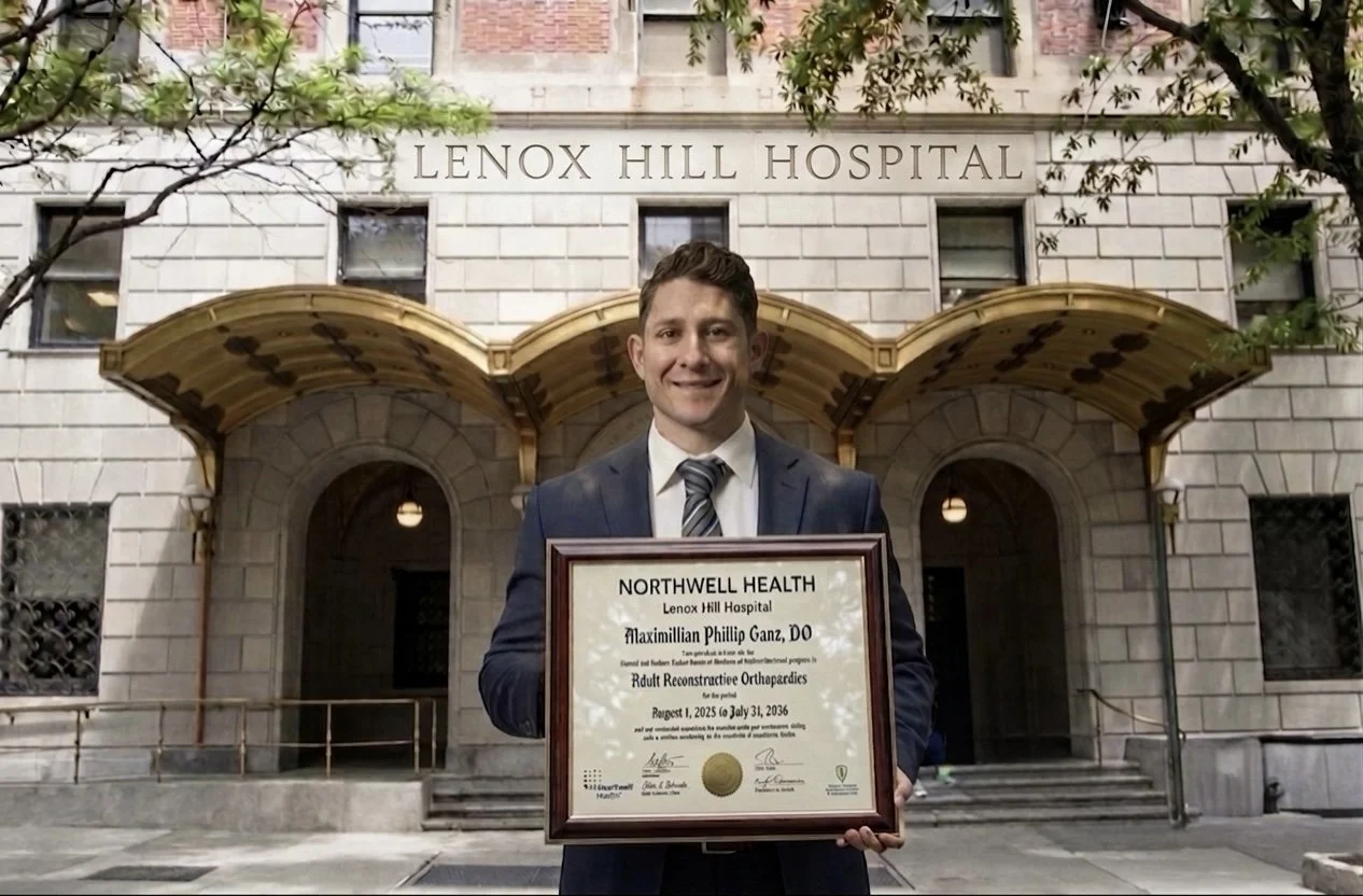 Man in a suit holding a framed certificate in front of Lenox Hill Hospital entrance. Total joint arthroplasty adult reconstruction fellowship diploma. Dr. Maximillian P. Ganz Total Joint arthroplasty surgeon