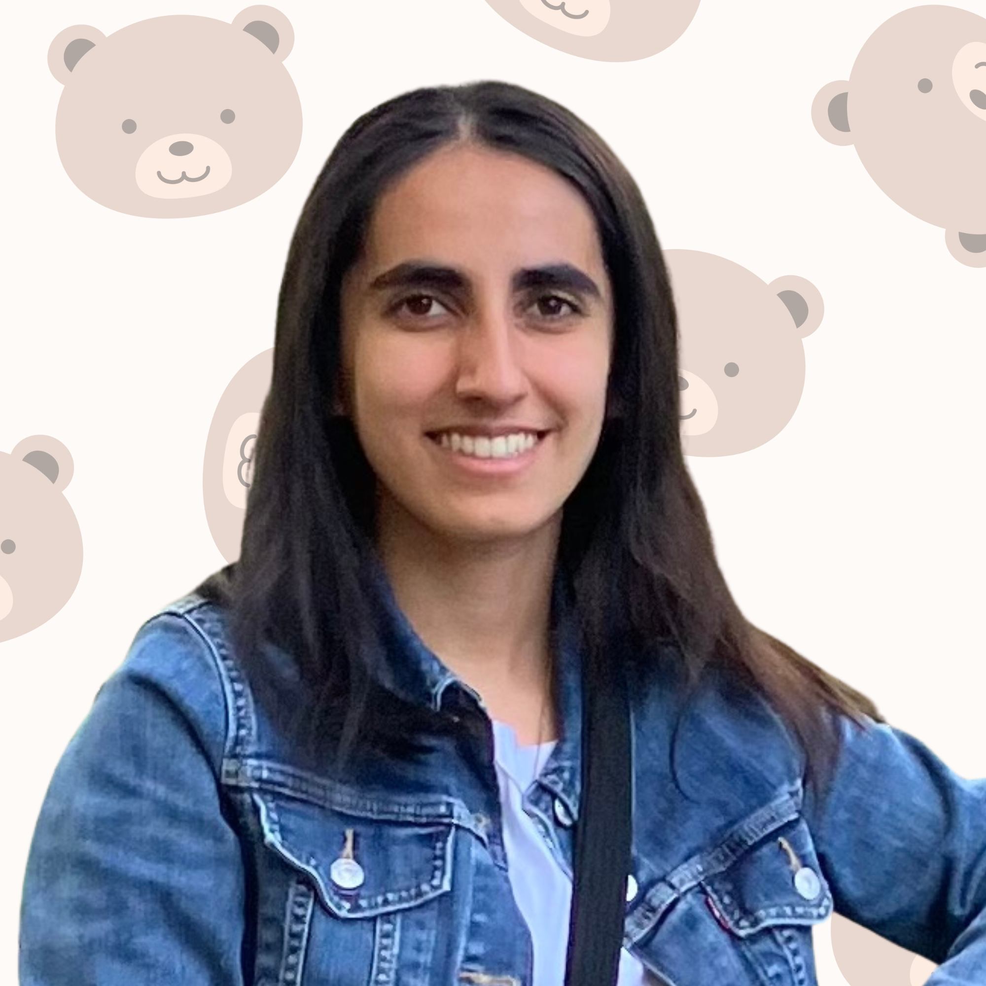 Young woman with long dark hair smiling, wearing a denim jacket and white shirt, standing in front of a background with bear faces pattern.