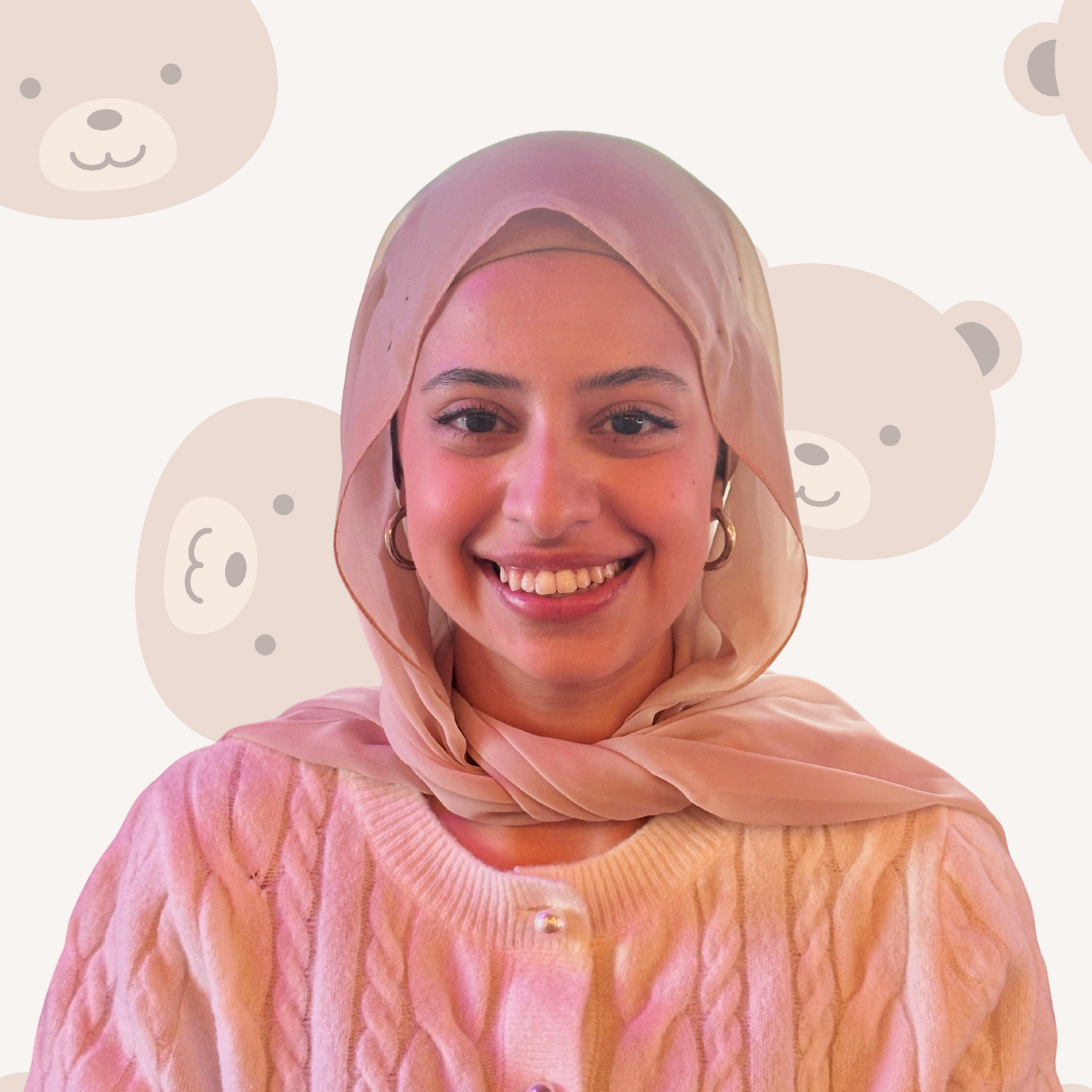Young woman with a bright smile wearing a pink hijab and a pink sweater with pearl buttons, against a background with bear faces.