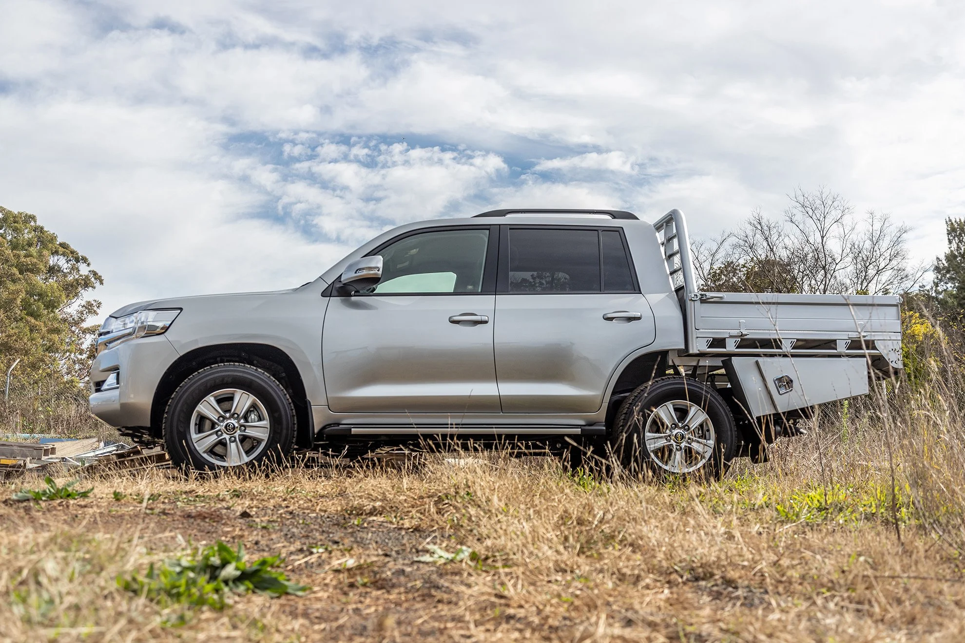 Silver pickup truck parked on grassy field under cloudy sky.