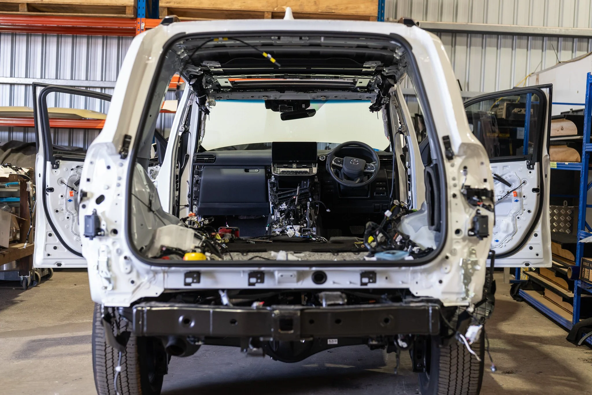 Front view of a partially assembled vehicle with the interior exposed, in a workshop setting.