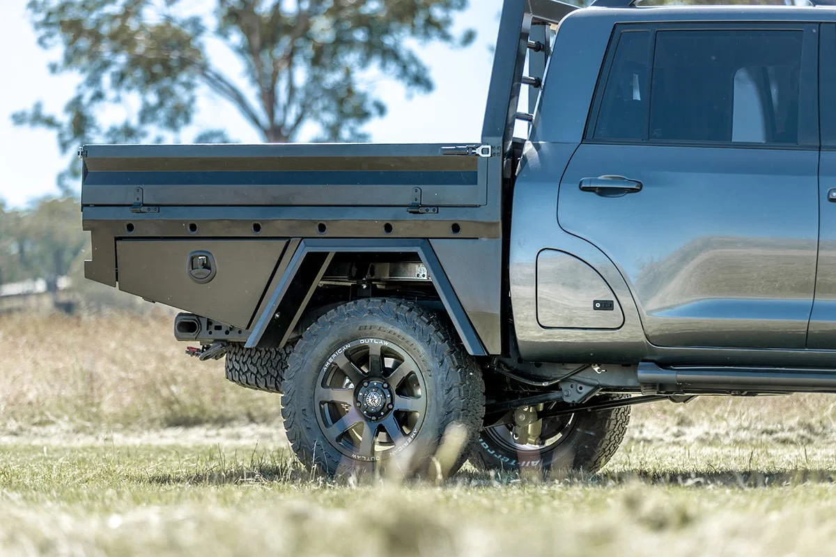 Close-up of a black pickup truck with a flatbed in an open field.