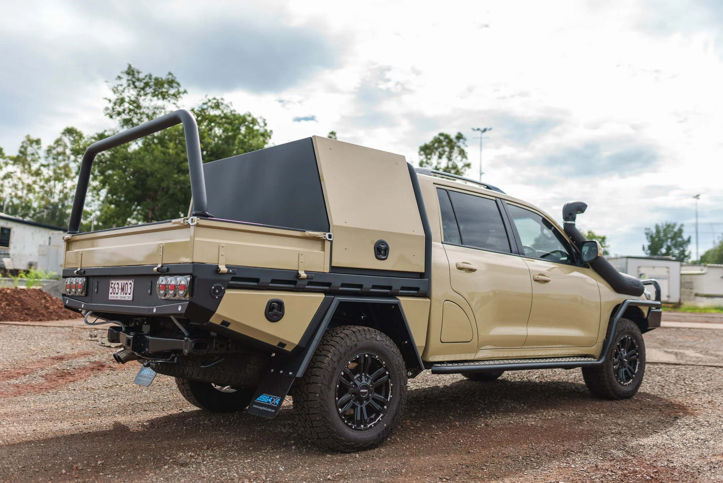 Beige off-road pickup truck with a black roof rack, black wheels, and a custom storage compartment on the back.