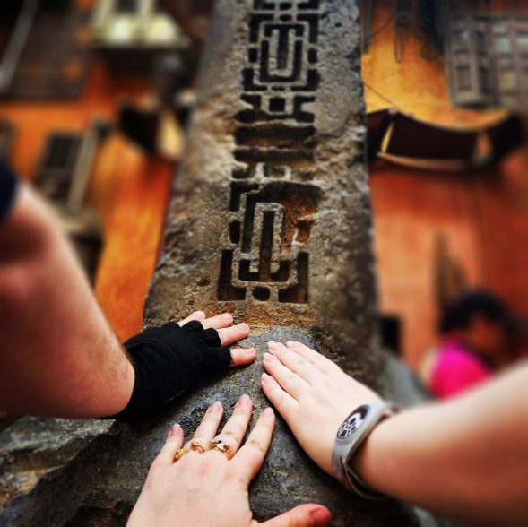 The obelisk in the center of the Marketplace in Batuu at WDW in Florida, three hands touching the base solemnly together.