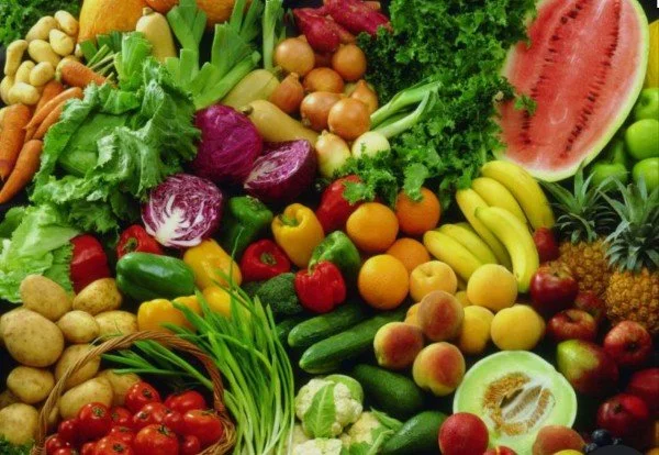 Assorted fresh fruits and vegetables including watermelon, bananas, pineapples, broccoli, lettuce, tomatoes, peppers, potatoes, and cucumbers.