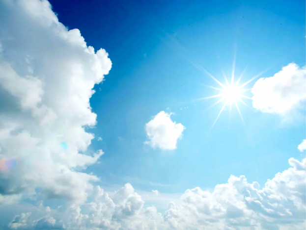 Bright sun shining in a partly cloudy blue sky.