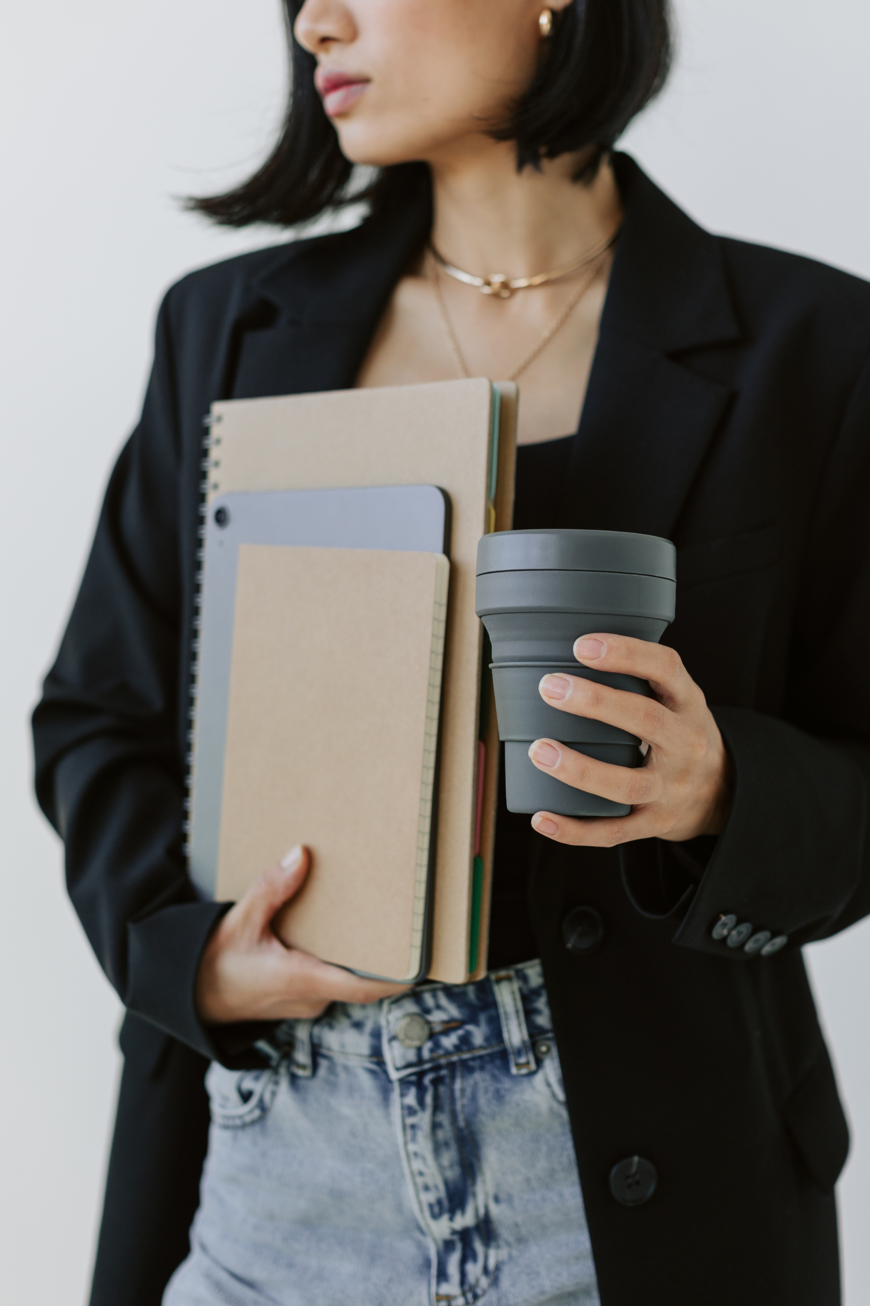 Woman arts worker holding multiple notepads and coffee