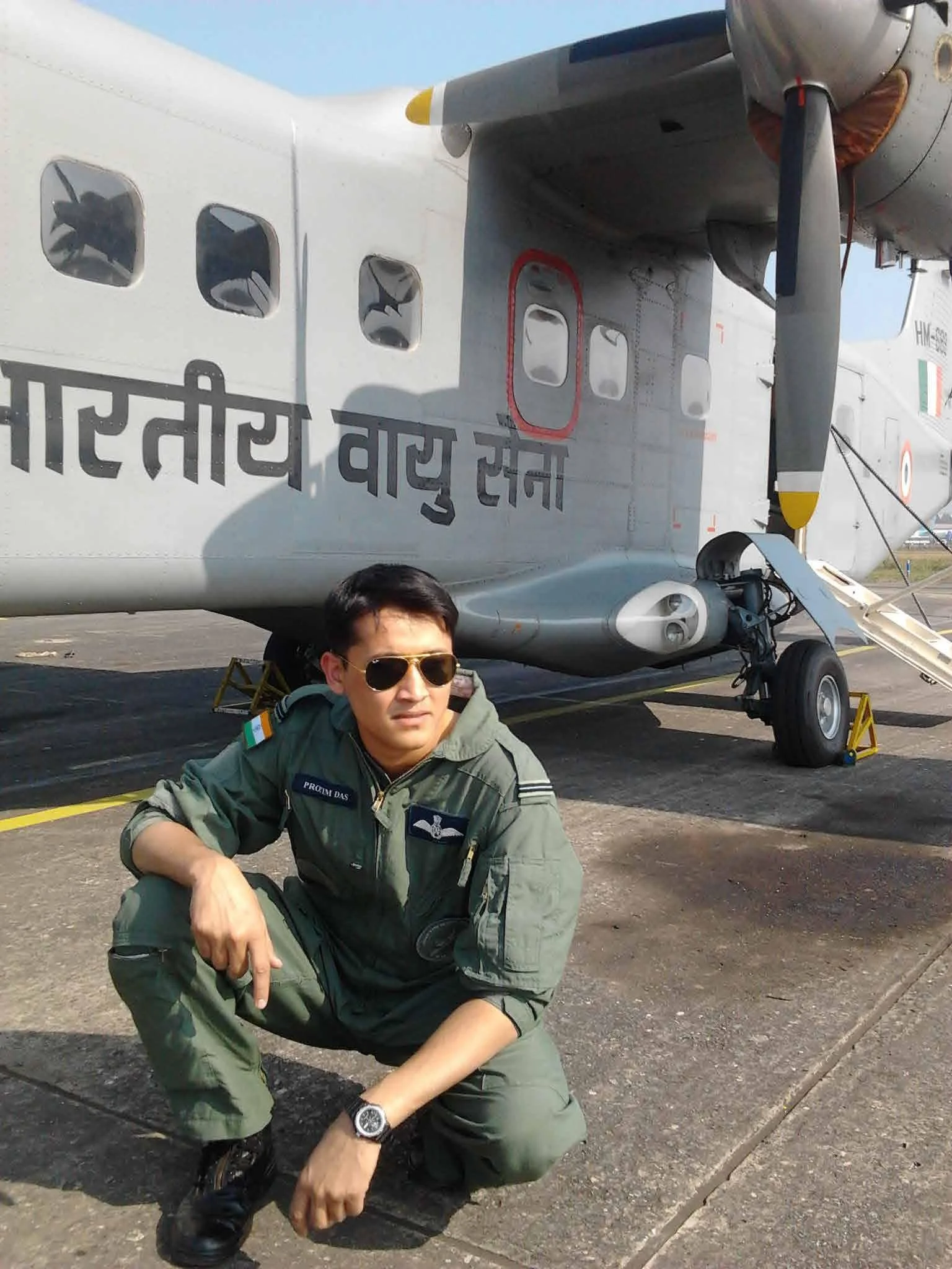 A man in military flight suit wearing sunglasses crouches next to a military aircraft with Hindi text on its side, on an airstrip. He is the founder of MyCore The fitness space in Bengaluru