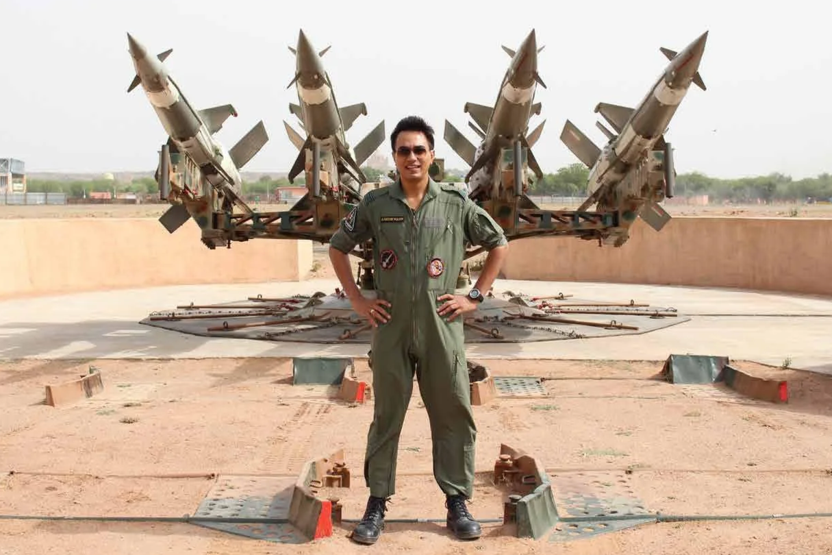 A person in a military jumpsuit standing in front of a display of fighter jets outdoors on a concrete pad.He is the founder of MyCore The fitness space in Bengaluru