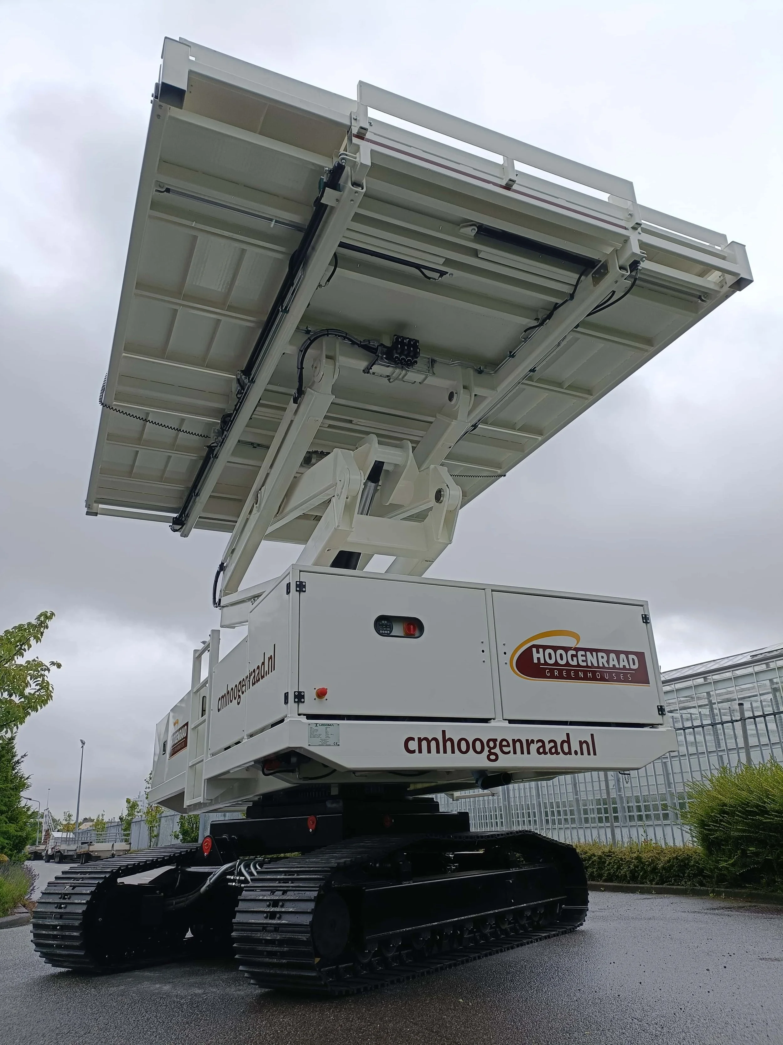 Een hoogwerker met een grote witte platform en rupsen