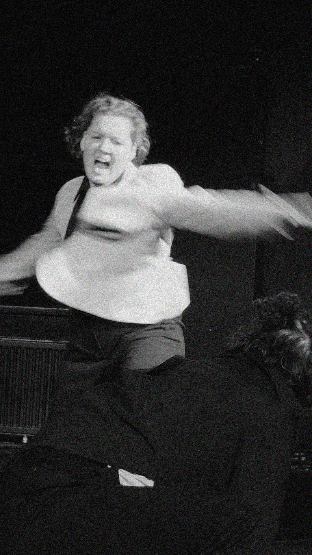 Chriara Ratz. Schülerin der internationalen Schauspiel-Akademie für Film und Theater in Hamburg. Frau mit offenem Mund, wild mit Armen gestikulierend, auf einer Bühne im MUT! Theater in Hamburg.