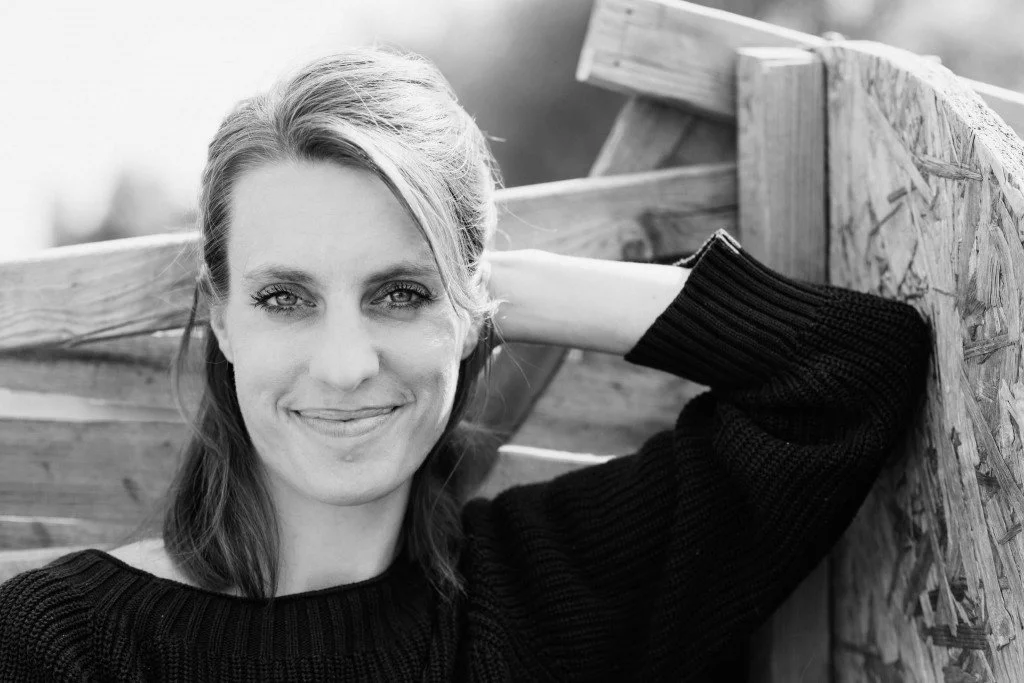 Anna Kriete Busch - Dozentin der internationalen Schauspiel-Akademie für Film und Theater in Hamburg. Eine lächelnde Frau mit braunen Haaren, trägt schwarzen Pullover, lehnt an einem Holzboot.