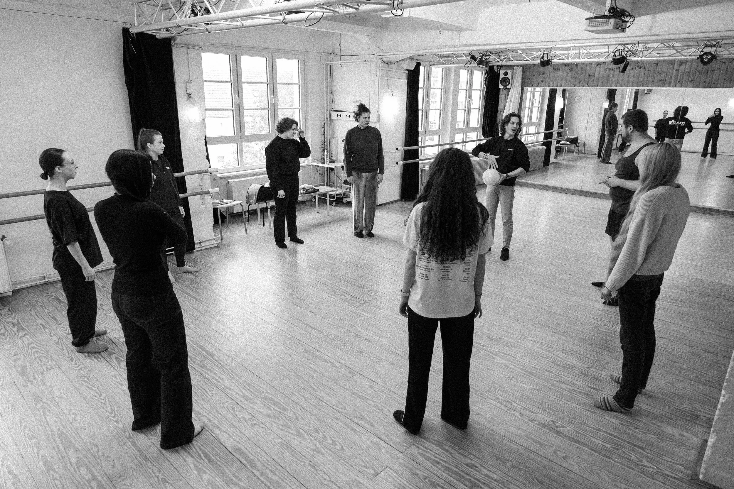 Gruppe von Menschen in einem Tanzstudio, die sich für einen Tanz- oder Bewegungskurs versammelt haben, mit Spiegeln an der Wand.
