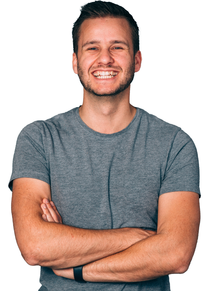 Een lachende man met armen over elkaar, draagt een grijs T-shirt en heeft kort, donker haar.