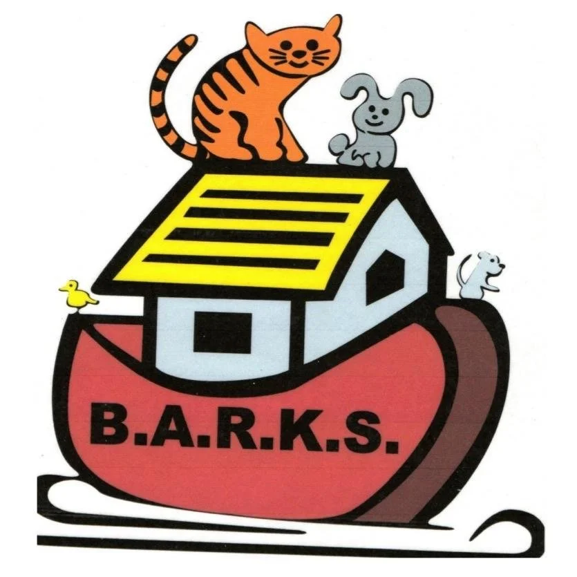 Logo featuring a house on a red leash with the word B.A.R.K.S. and four cartoon dogs of different breeds and colors on and around the house.