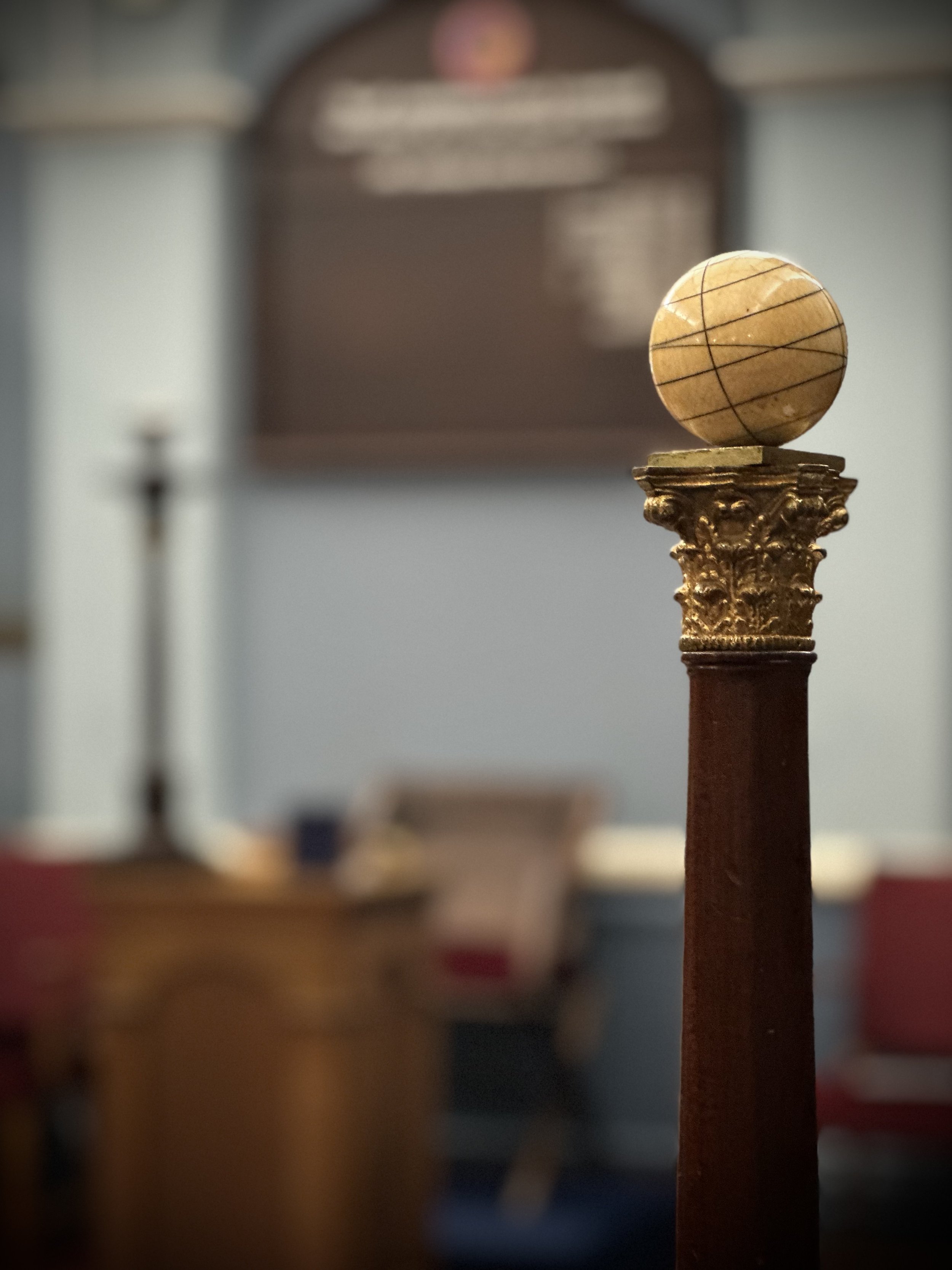 A column on a decorative gold-colored capital on a wooden pedestal