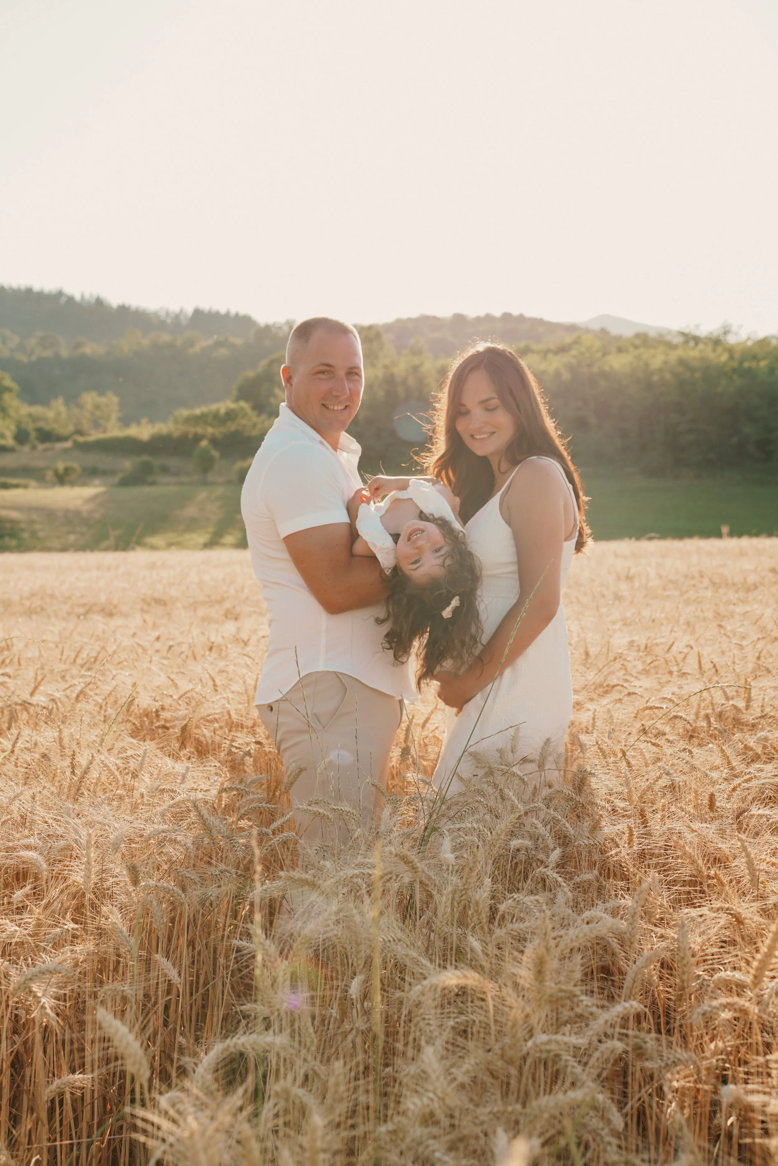 Famille dans un champ de blé au coucher du soleil