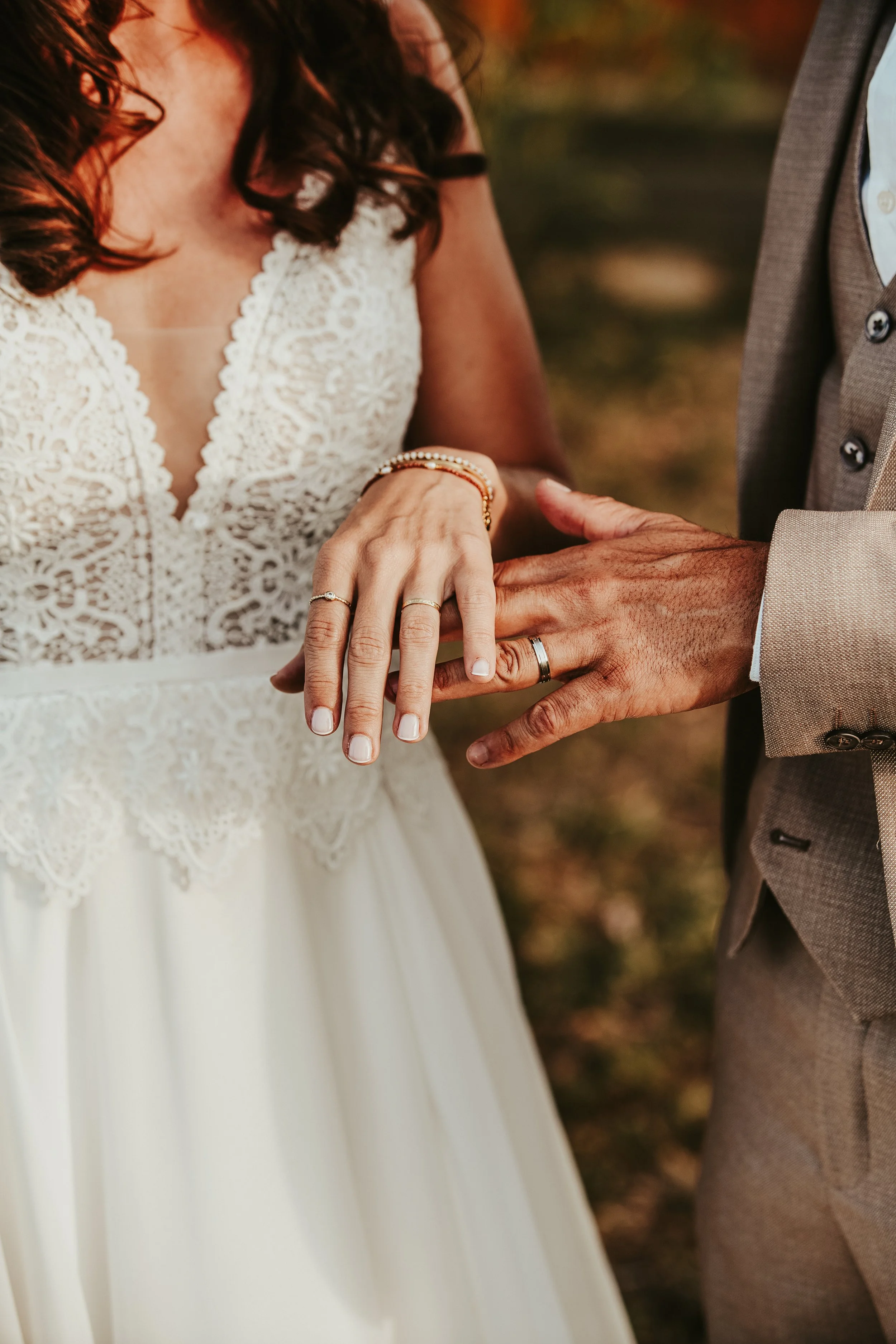 Une femme en robe de mariage et un homme en costume échangent des anneaux de mariage, concentrés sur leur union.