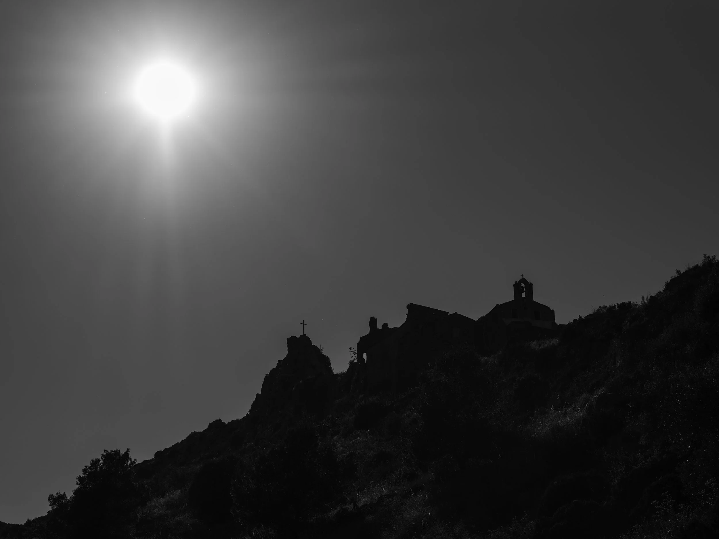Sous le silence du ciel, une lumière écrasante suspend les ruines dans le silence du paysage, comme une présence oubliée au bord du vide.