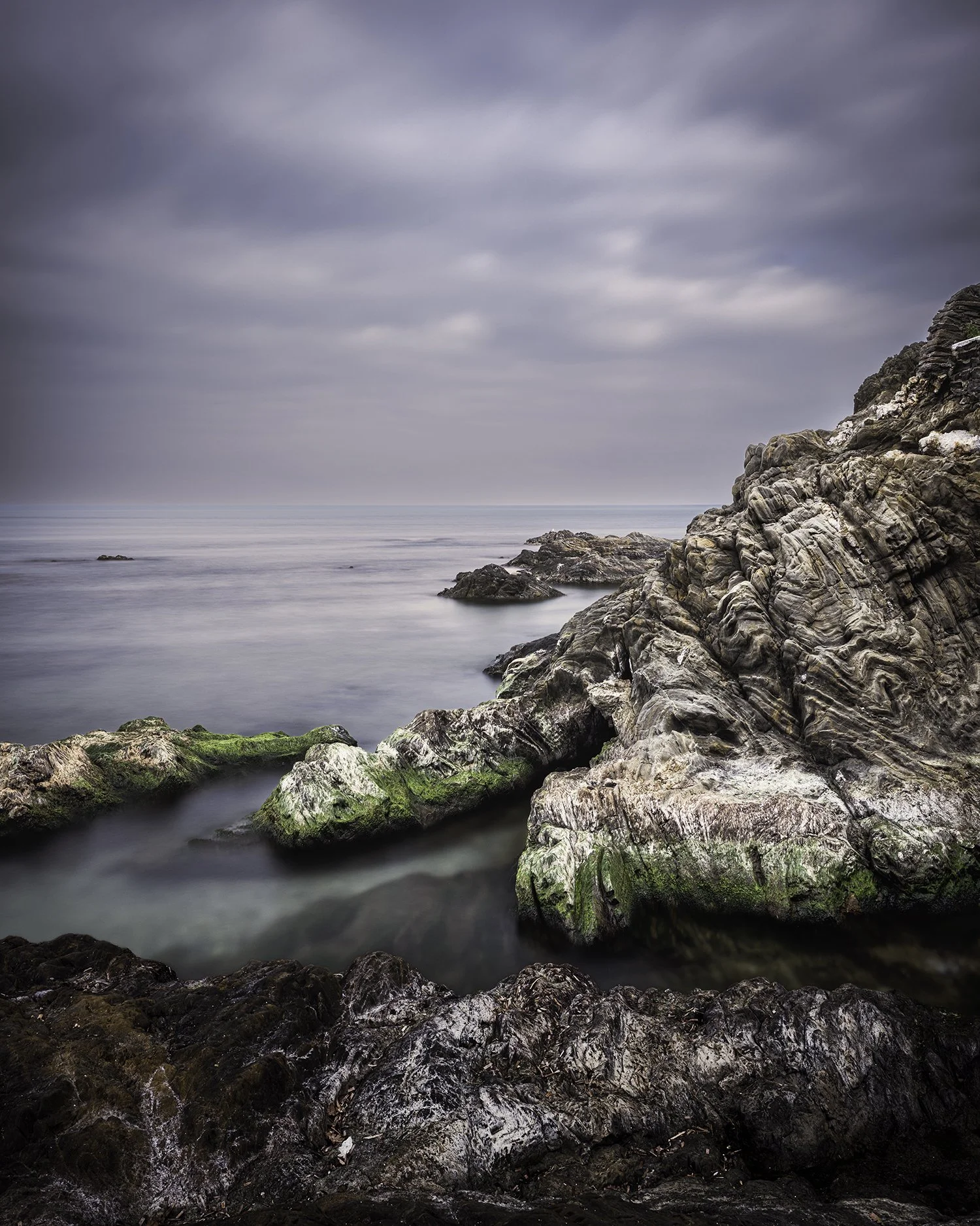Silence minéral — El Racó, hiver 2026. Une série qui explore la présence silencieuse de la roche face au mouvement de la mer. Les strates apparaissent comme une mémoire lente, façonnée par le temps et l’eau. La mer adoucit, efface, transforme. La pie