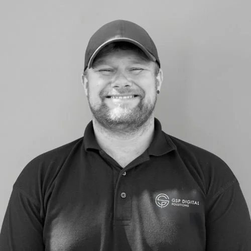 GSP Digital Solutions technician wearing branded polo and cap while smiling at the camera.