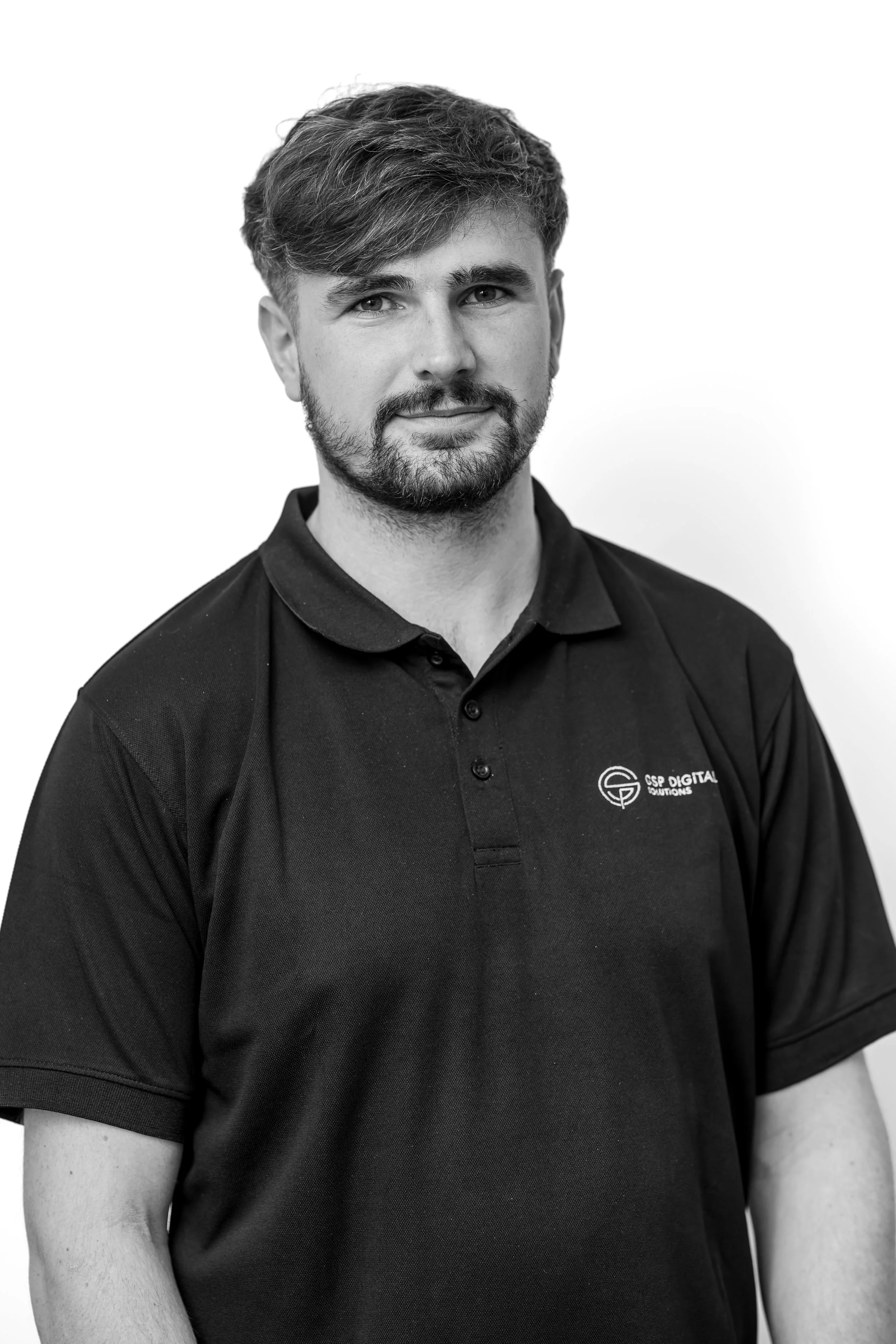 Smiling GSP Digital Solutions employee wearing branded T shirt in front of light background.