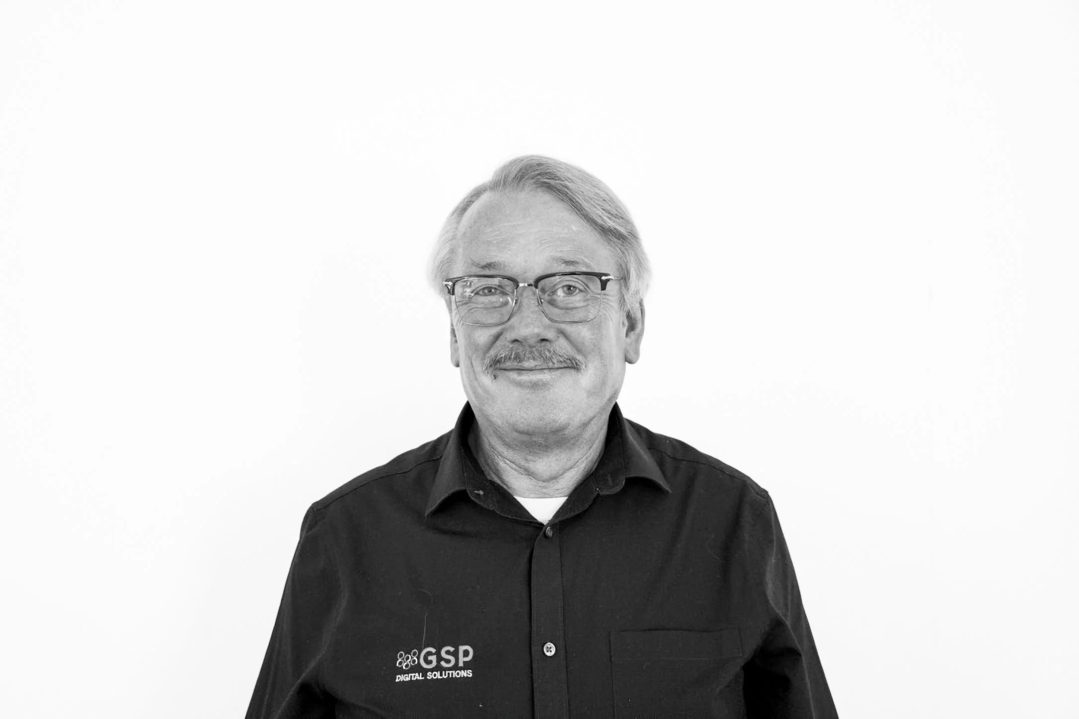 Experienced GSP Digital Solutions staff member wearing branded polo shirt and glasses.