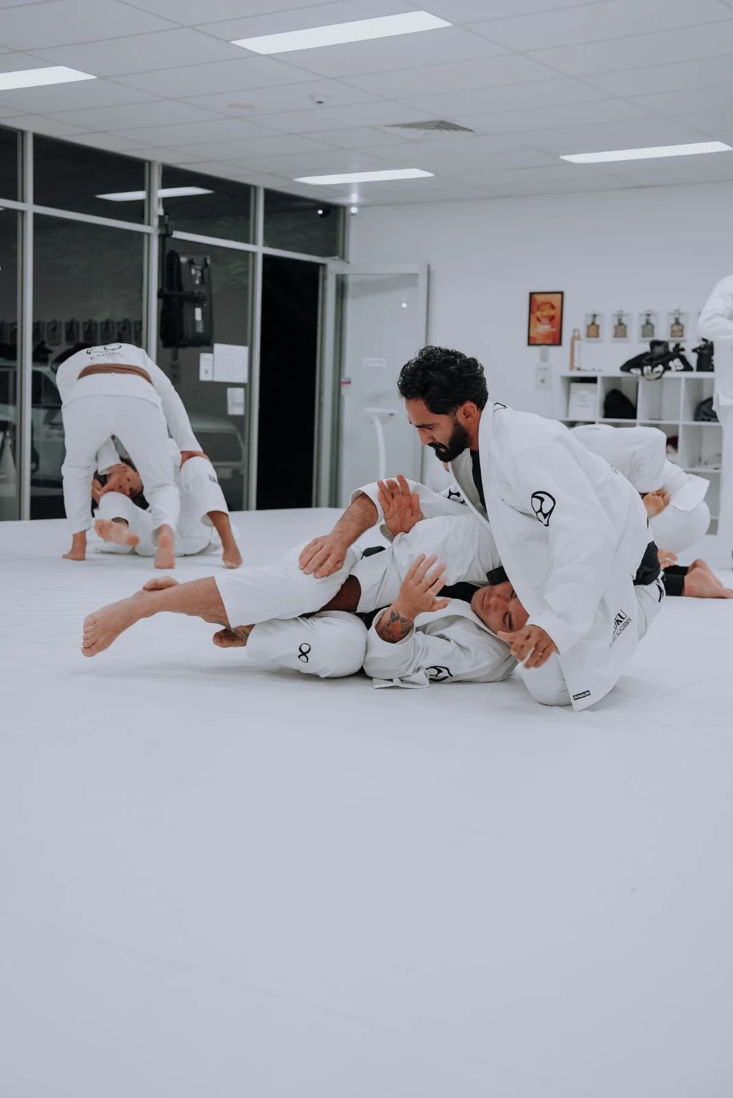 Adults training Brazilian Jiu-Jitsu on the mats at Kazoku Jiu Jitsu Academy in Varsity Lakes