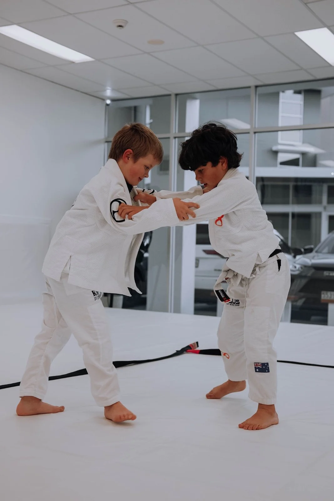 Two kids in white gis training Brazilian Jiu-Jitsu at Kazoku Jiu Jitsu Academy in Varsity Lakes