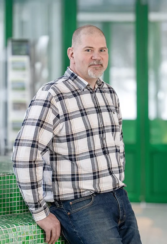 En fastighetsansvarig står i ett rum med gröna väggar och hyllor.