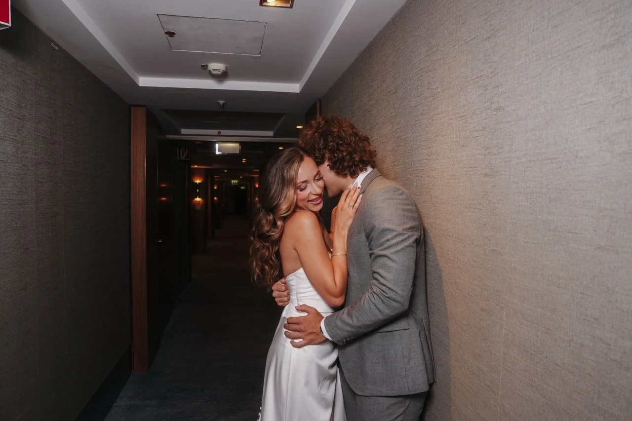 A couple in wedding attire embracing in a dimly lit hallway