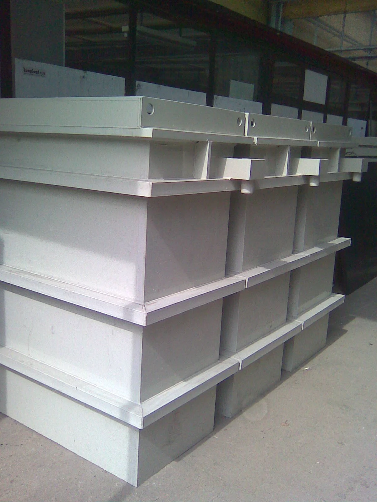 Stacked beige plastic storage crates outside, with a building in the background.