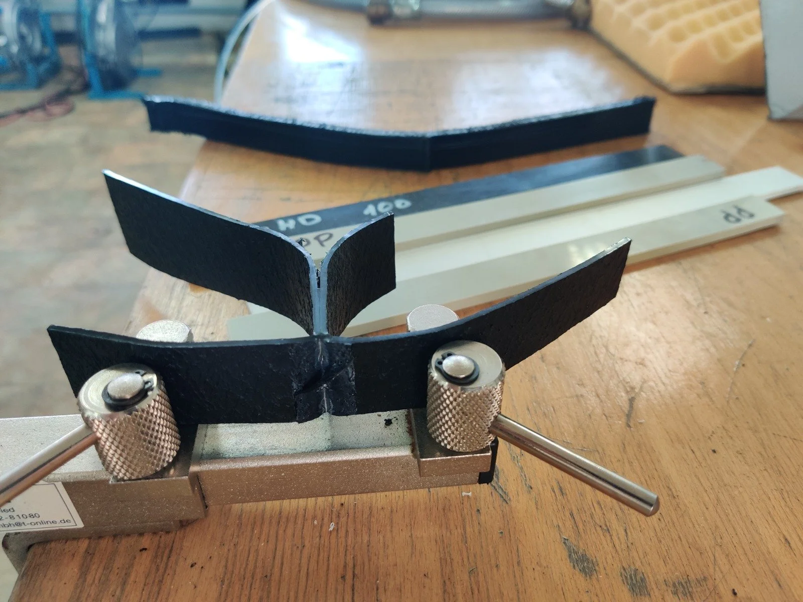Close-up of a marking gauge tool on a wooden workbench, with black and white measuring sticks in the background.
